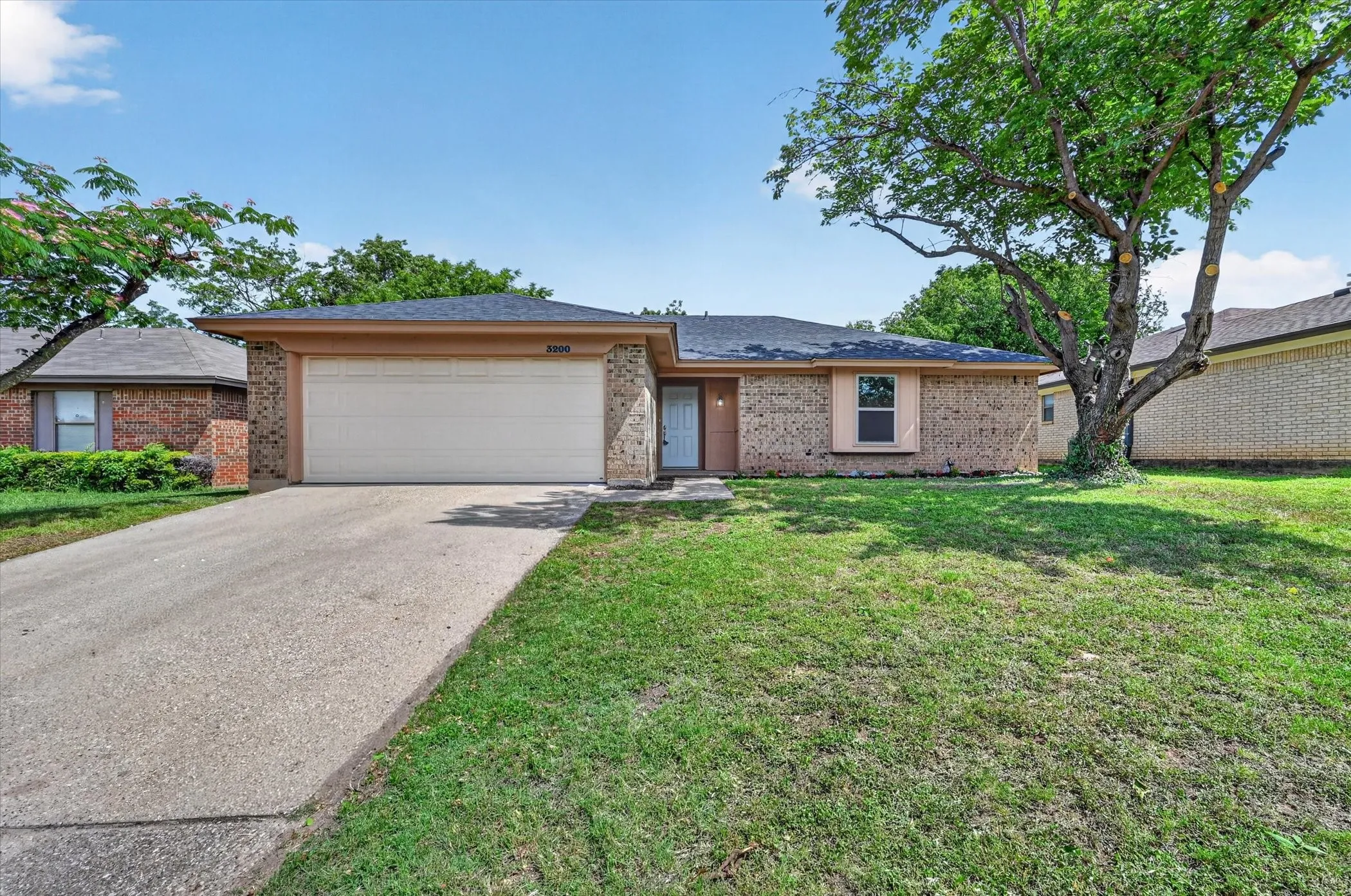 Single-story residence featuring brick and stone veneer accents, an attached two-car garage, and a concrete driveway