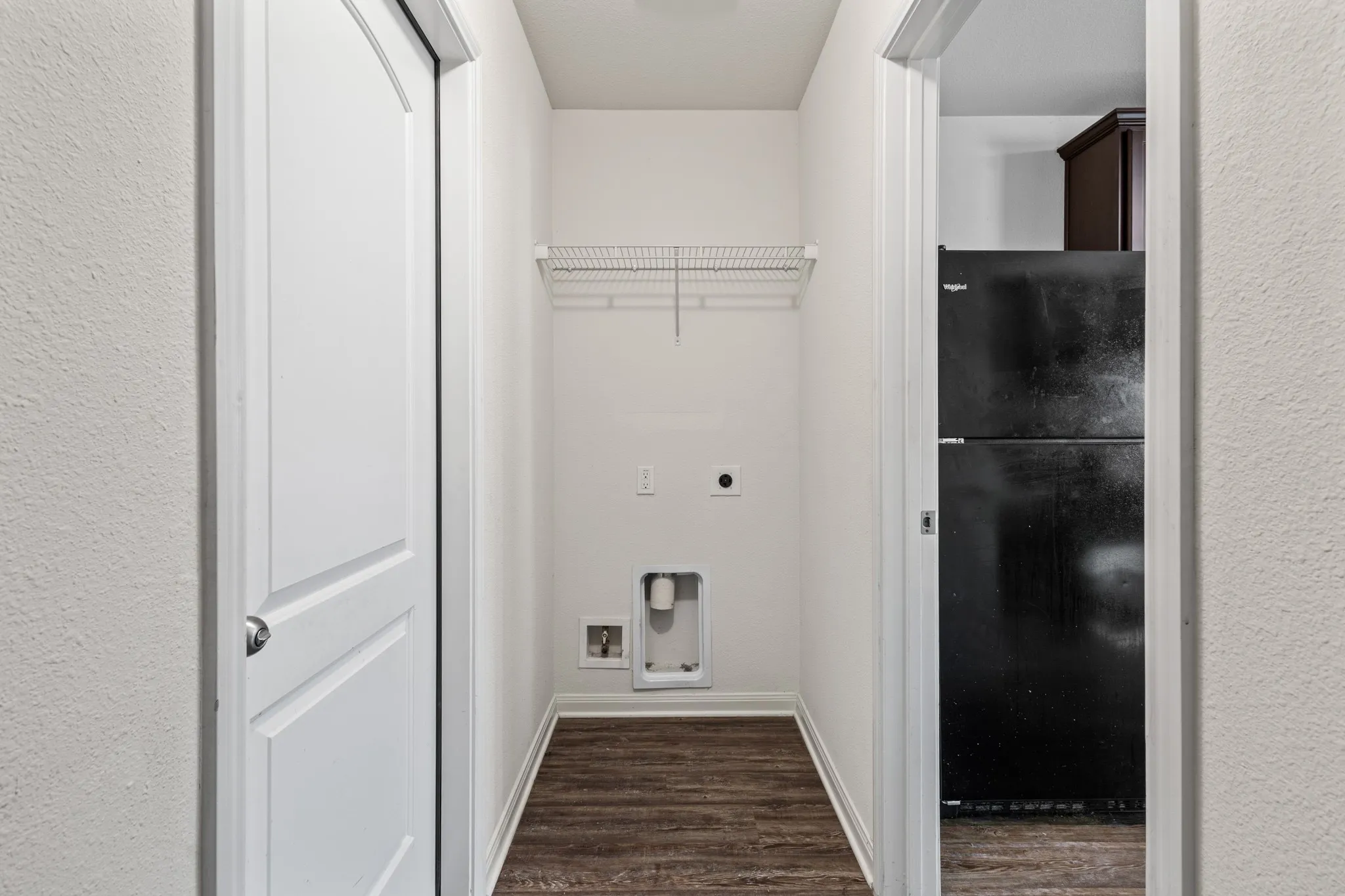 Dedicated laundry area featuring wood-finish flooring, white walls, and a wire shelving unit