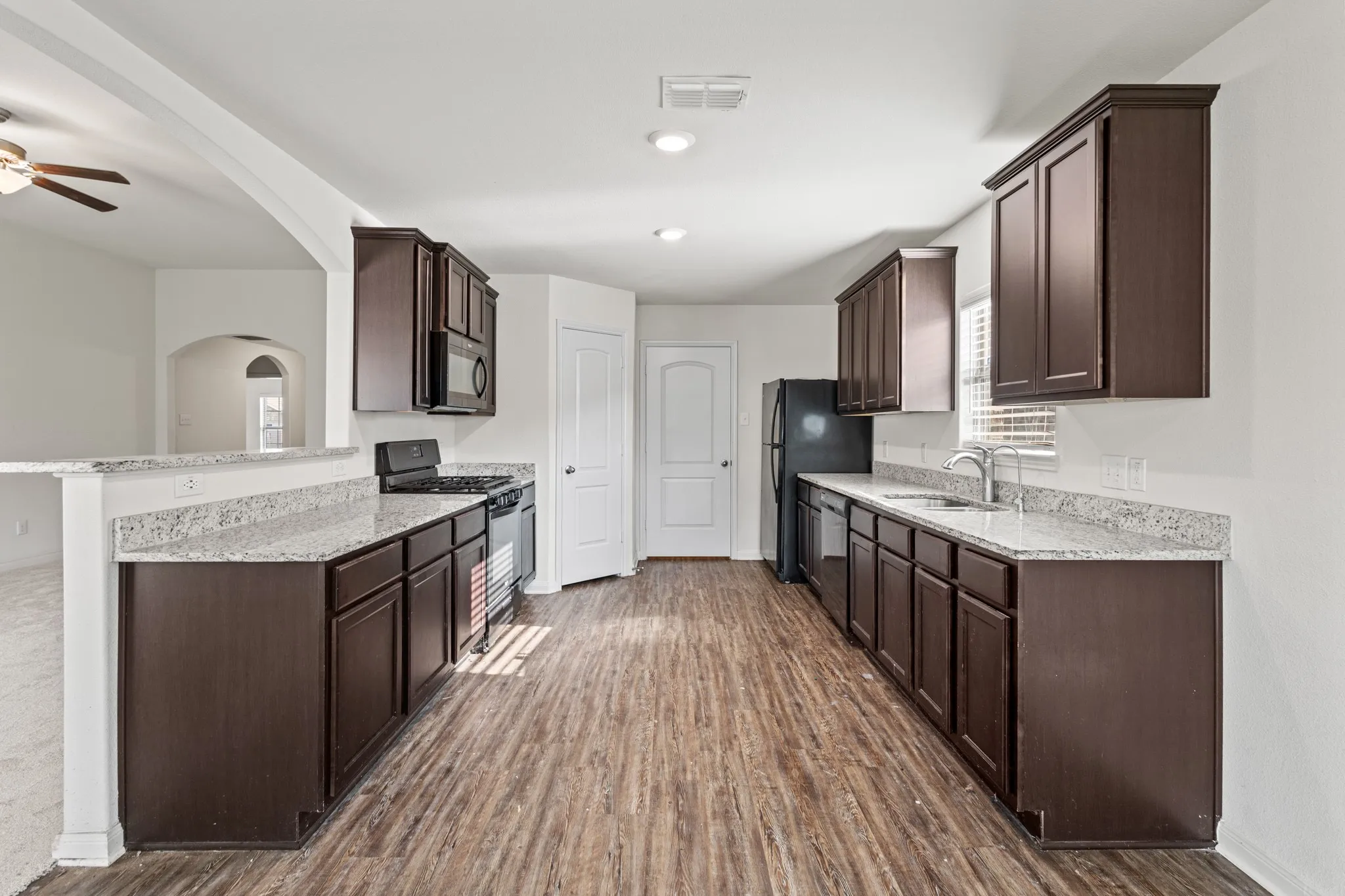 Modern kitchen featuring wood-finish flooring, dark wood cabinetry, and light-toned countertops