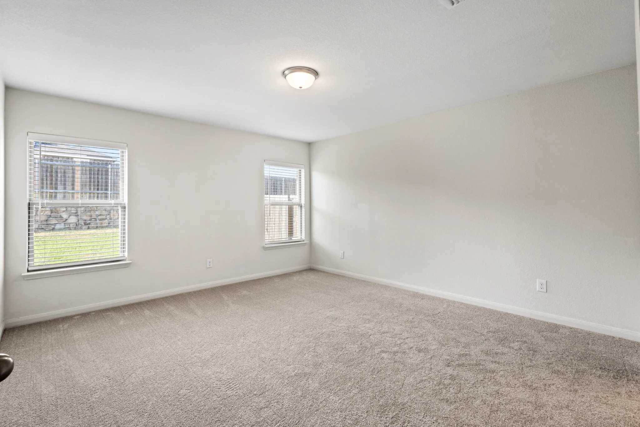 Spacious room featuring neutral carpeting, light-toned walls, and recessed windows with horizontal blinds