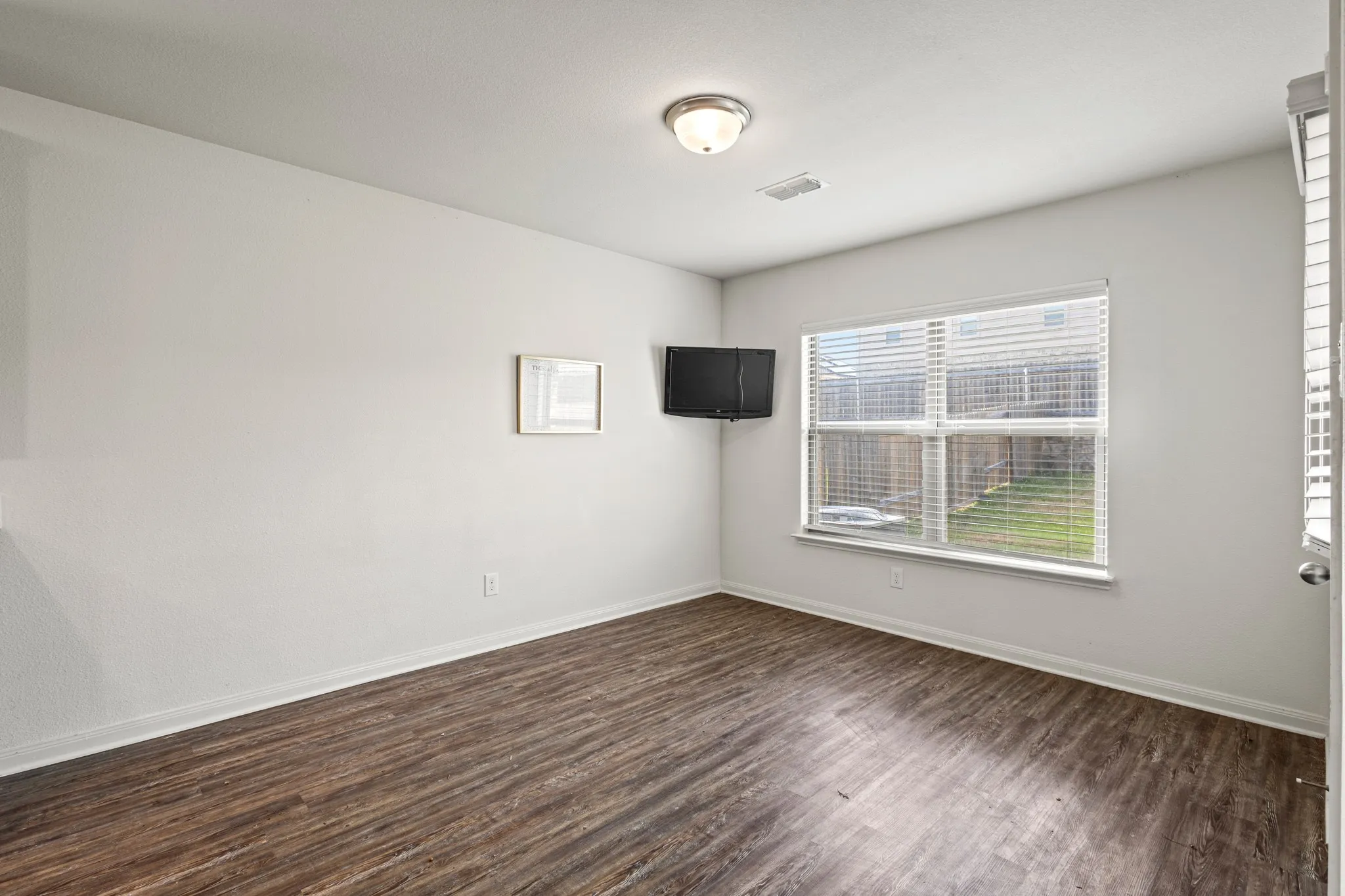 Neutral interior room featuring wood-finish flooring, white baseboards, and light-colored walls