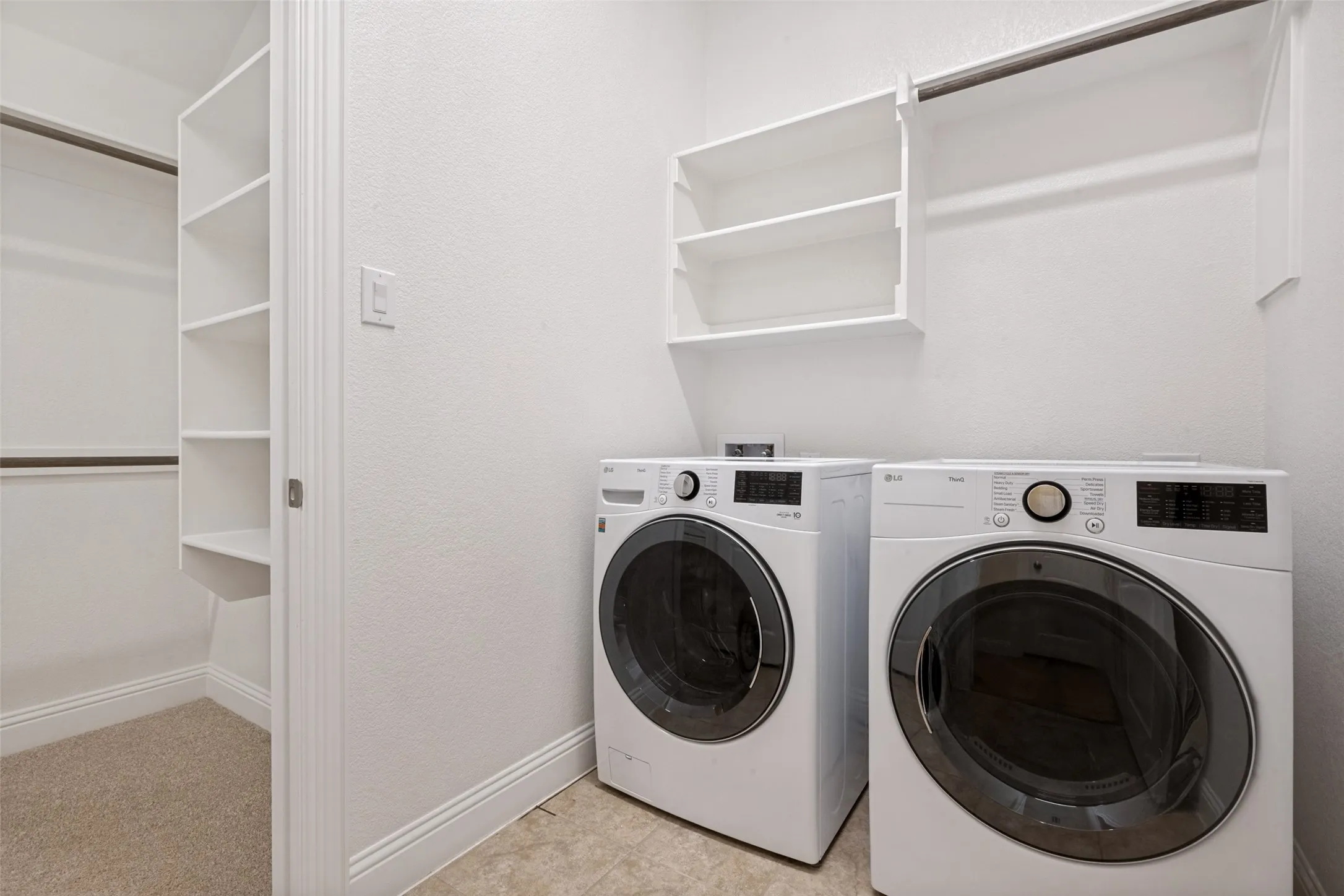Utility area featuring a built-in shelf unit, hanging rod, and tiled flooring