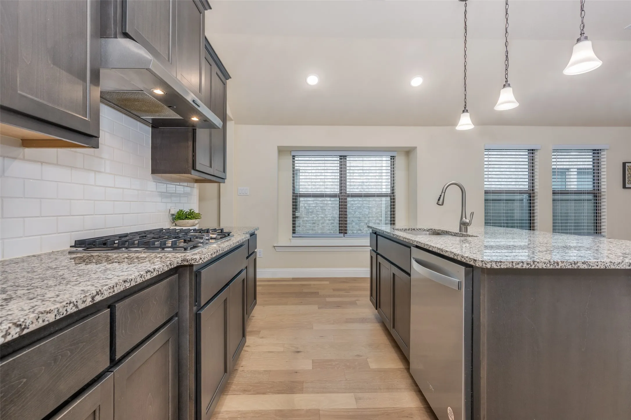 Contemporary kitchen featuring dark wood-finish cabinetry, granite countertops, and a subway tile backsplash