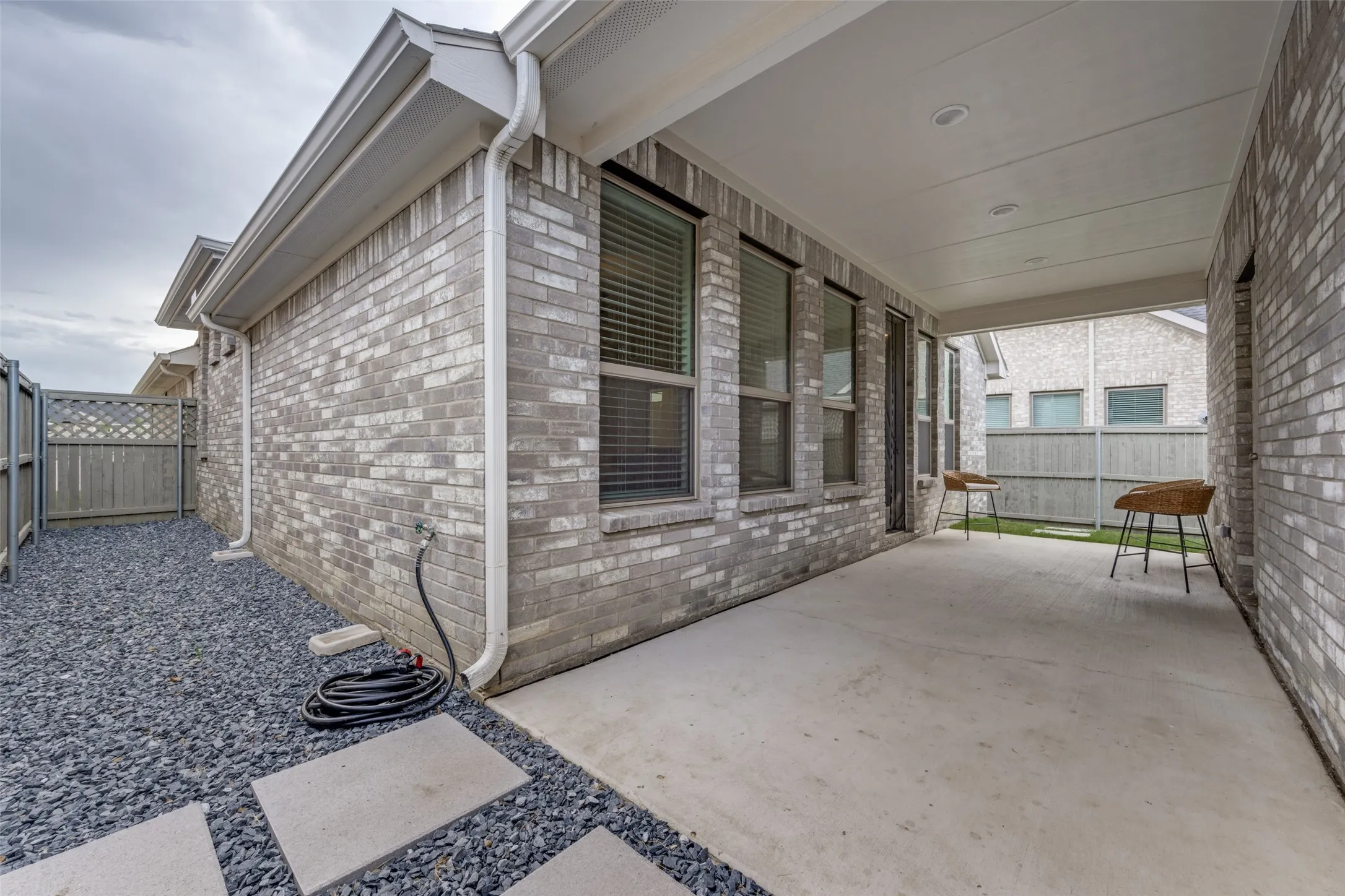 Covered concrete patio featuring recessed lighting and a brick exterior