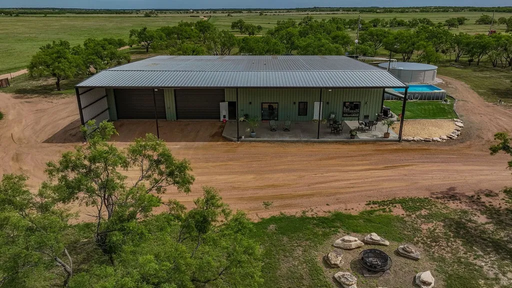 Front of the 9,000 sq ft barndominium. There are two oversized roll up doors, a covered concrete porch and plenty of parking for guests, trucks and trailers.