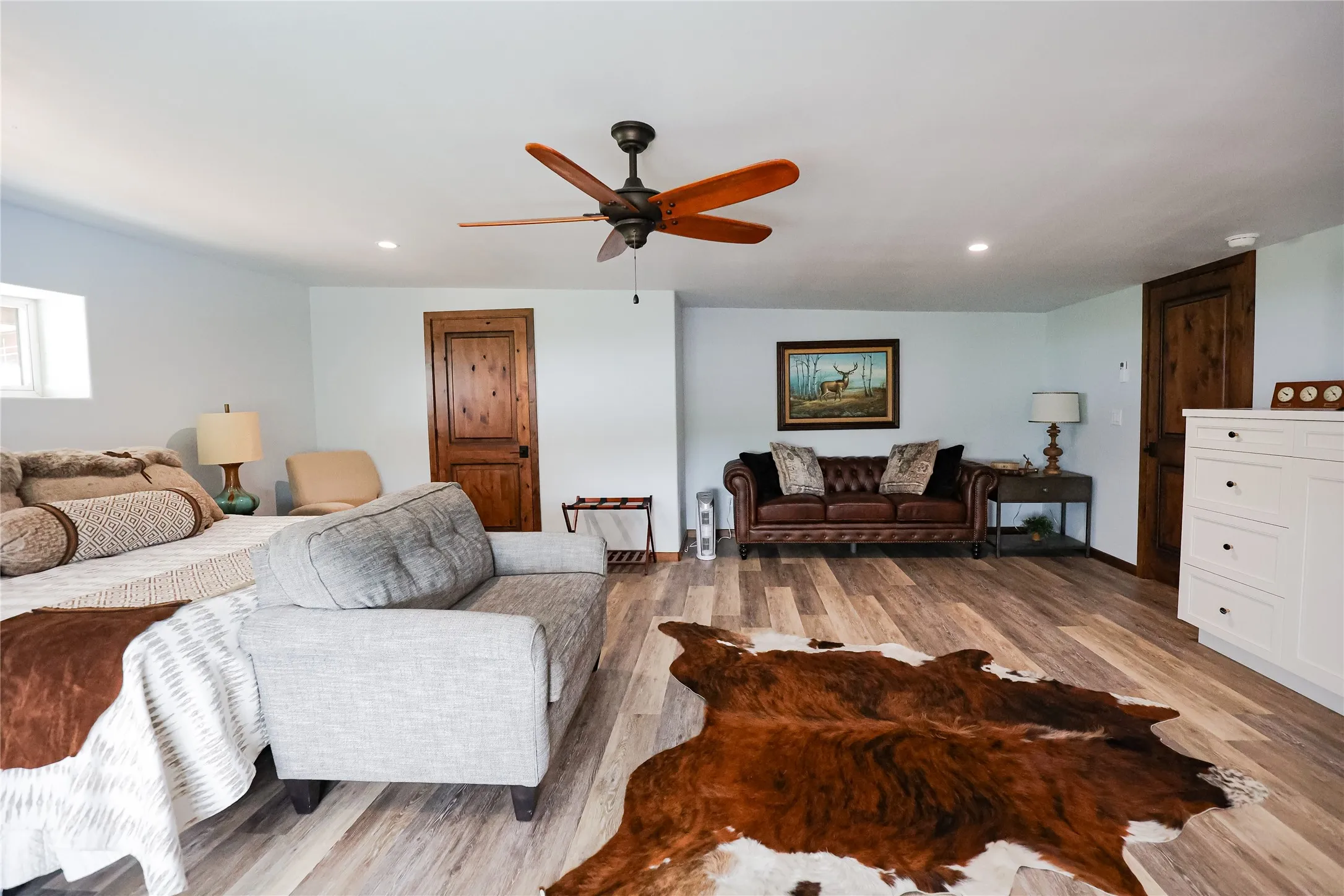 Spacious guest suite with a sitting area, built in storage, a ceiling fan and luxury vinyl plank floors. There's room for a king bed and furniture for long stays at this Texas ranch lodge.