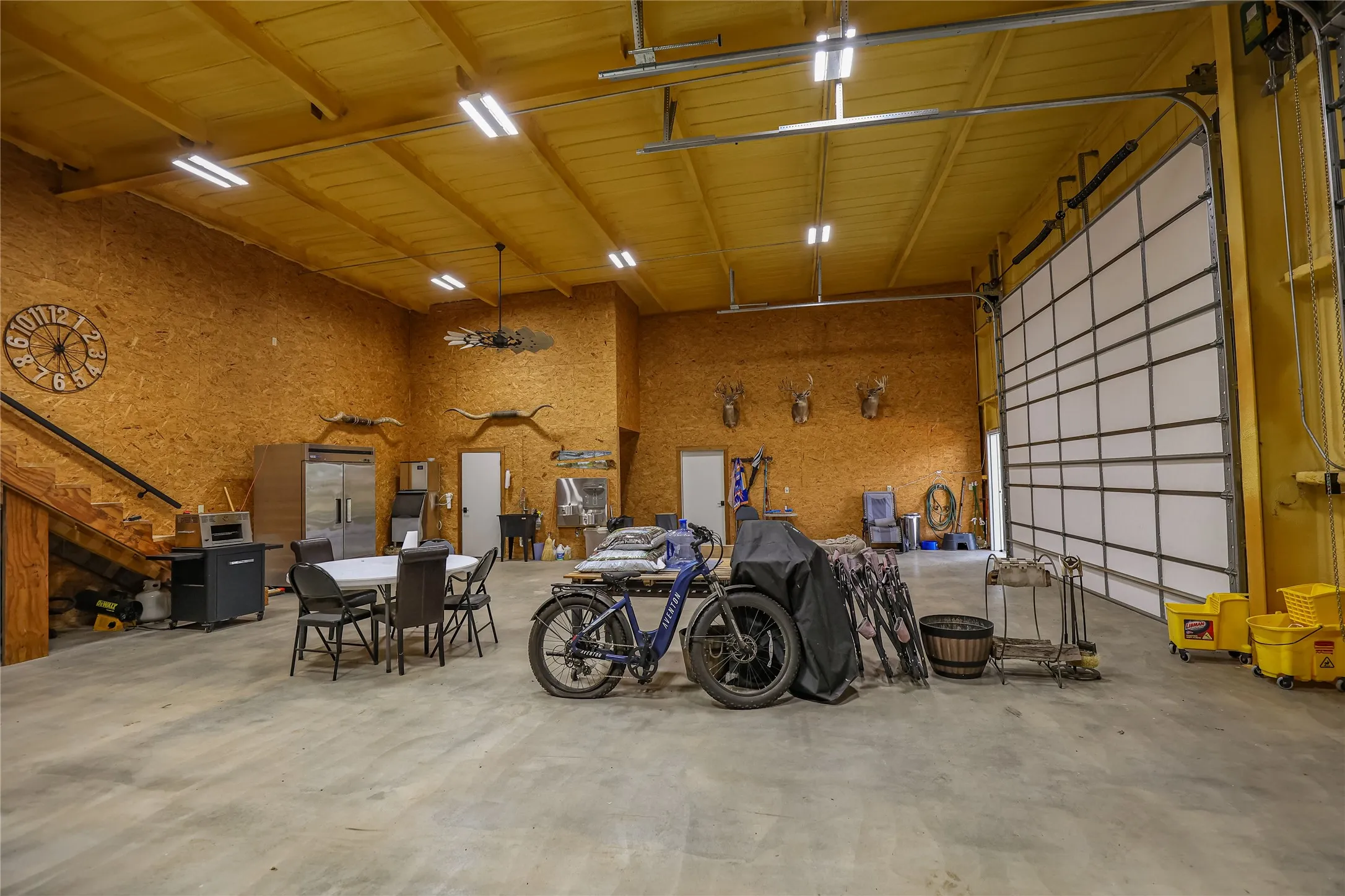 Shop interior with stairs to a loft, sealed concrete floor and room for equipment, a game room or a hunting camp gathering space.