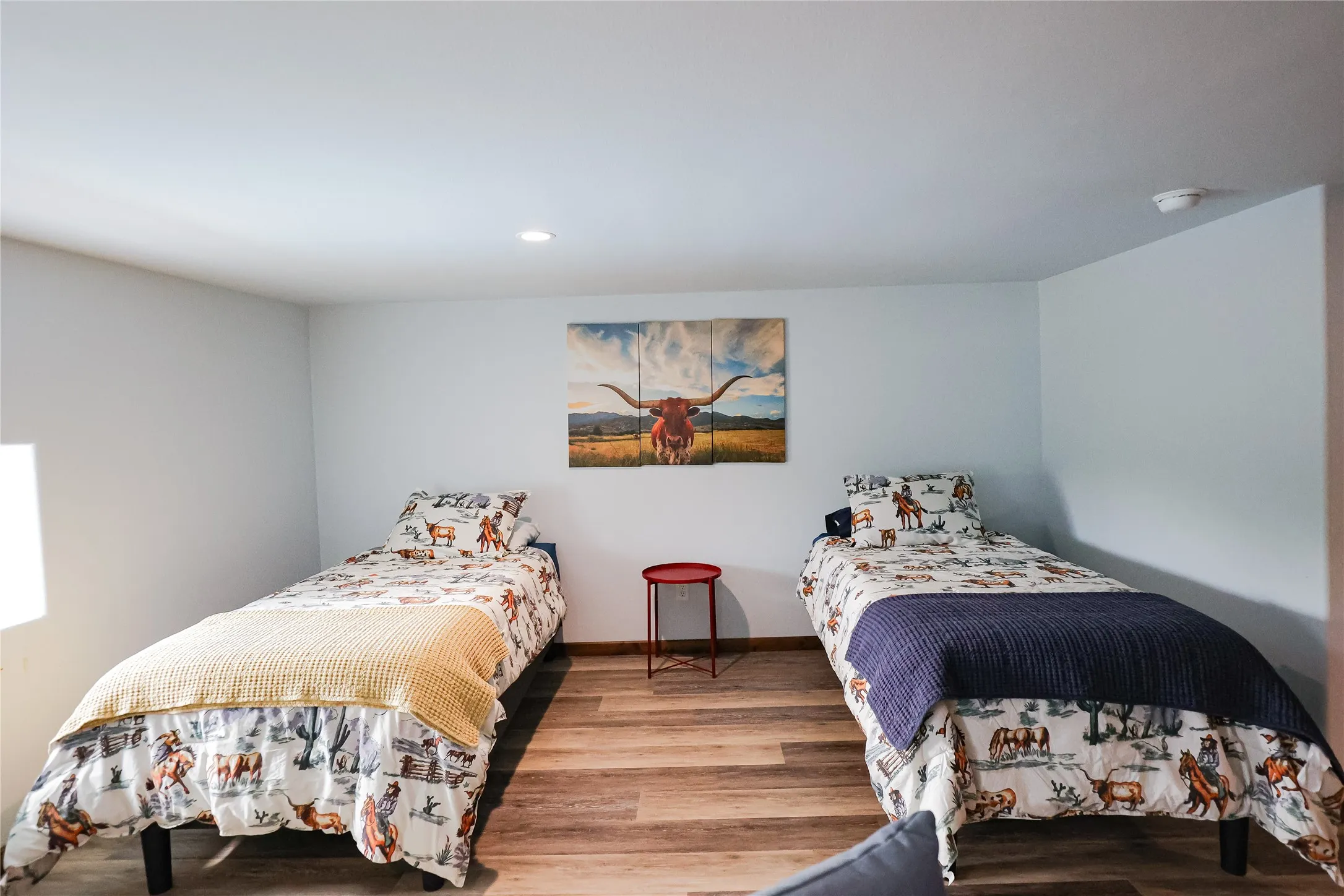 Spacious bunk room with two twin beds, luxury vinyl plank floors and recessed lighting. It's ready for hunting buddies, guests or retreat stays at this Texas ranch lodge.