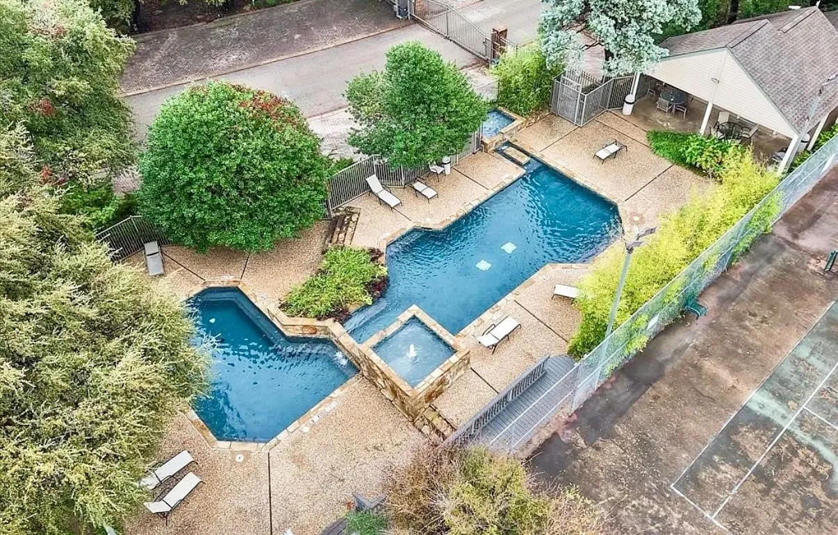 Multi-level swimming pool with integrated spa and water feature, surrounded by extensive stone-finish decking