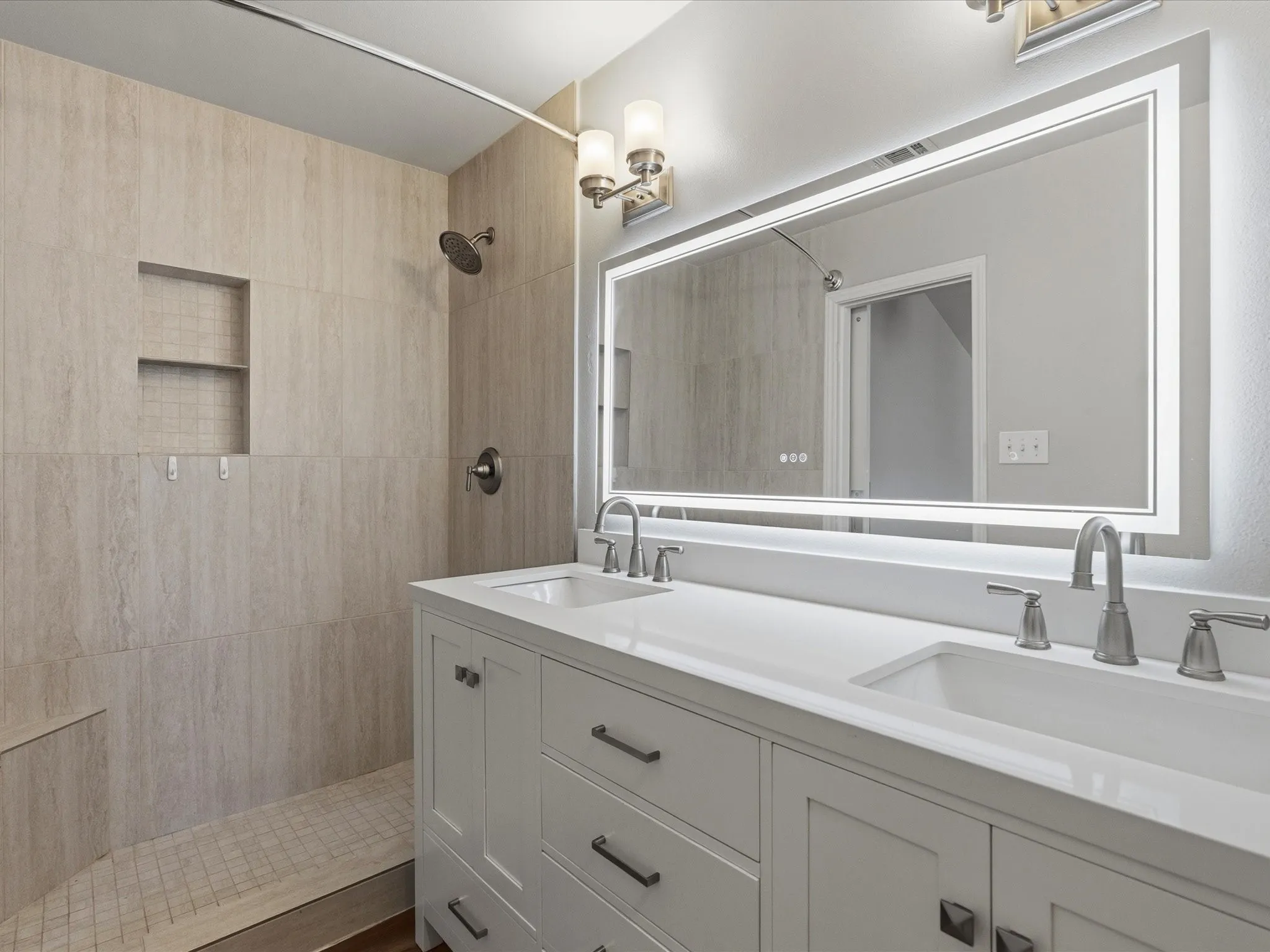 Updated bathroom featuring a double vanity with white cabinetry, integrated sinks, and brushed nickel fixtures