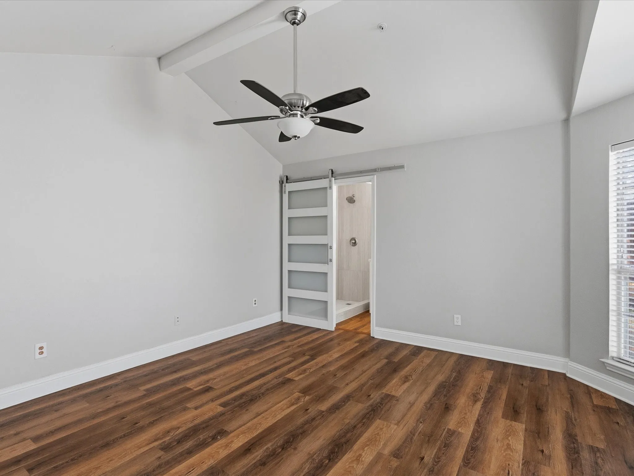 Master bedroom with en updated ensuite bathroom. Vaulted ceiling room featuring wood-finish flooring and a contemporary ceiling fan