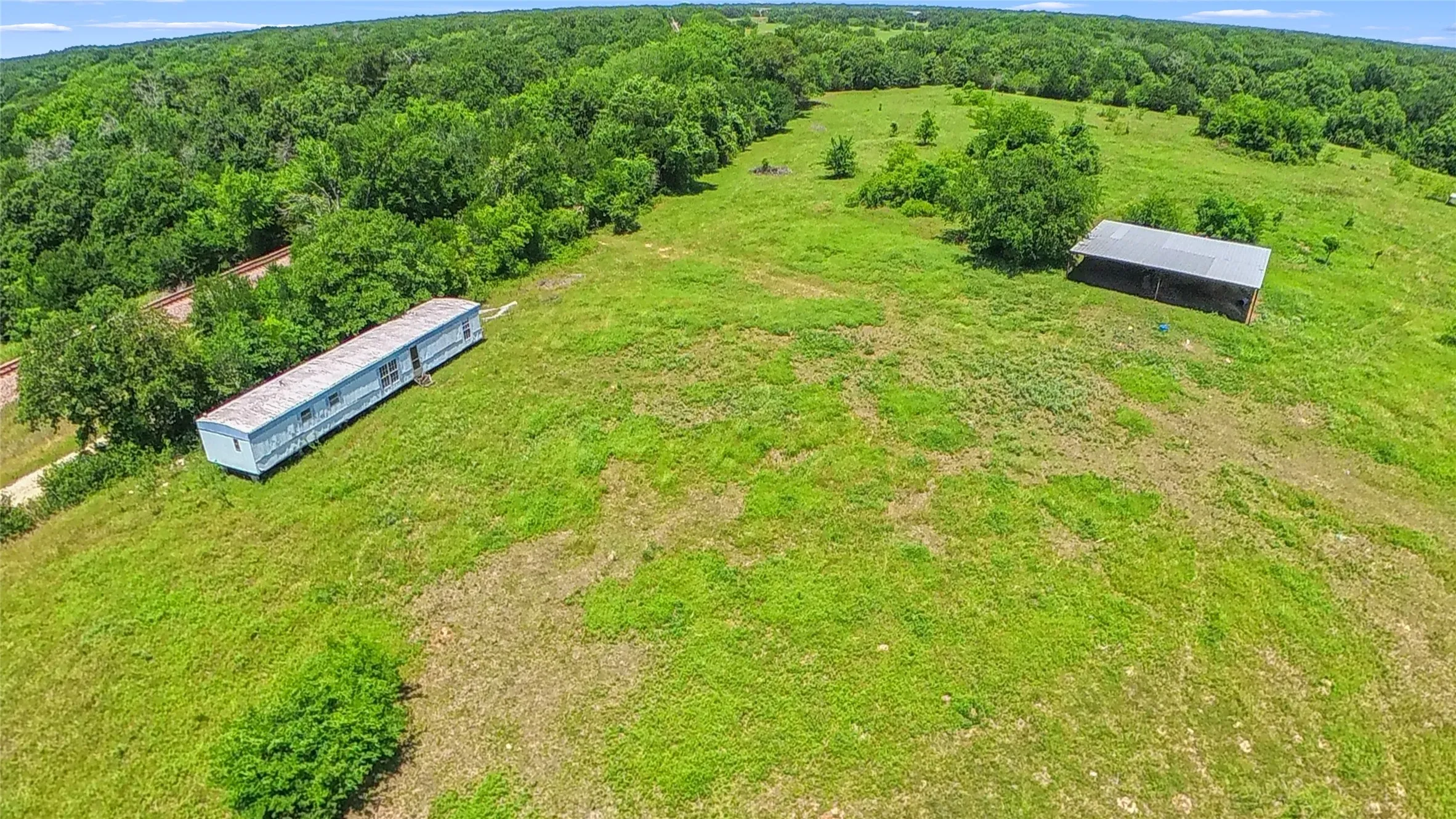 Expansive green acreage featuring a barn structure and a manufactured home