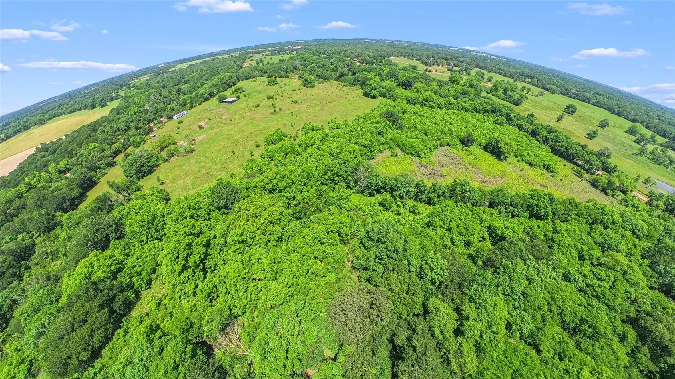 Expansive land parcel featuring diverse topography, including rolling hills and densely wooded areas