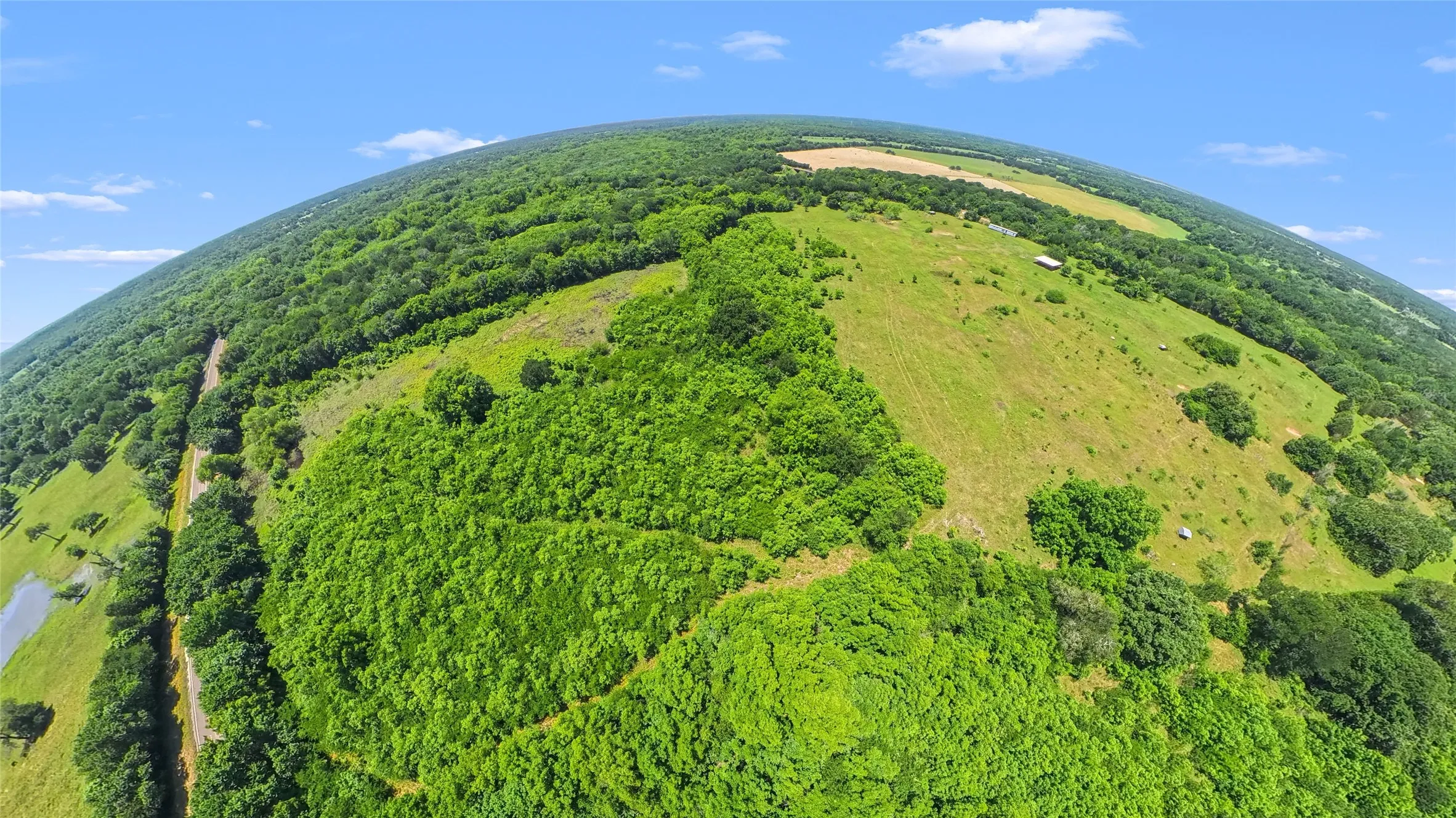 Expansive land offering diverse topography, including rolling green hills and dense mature woodlands