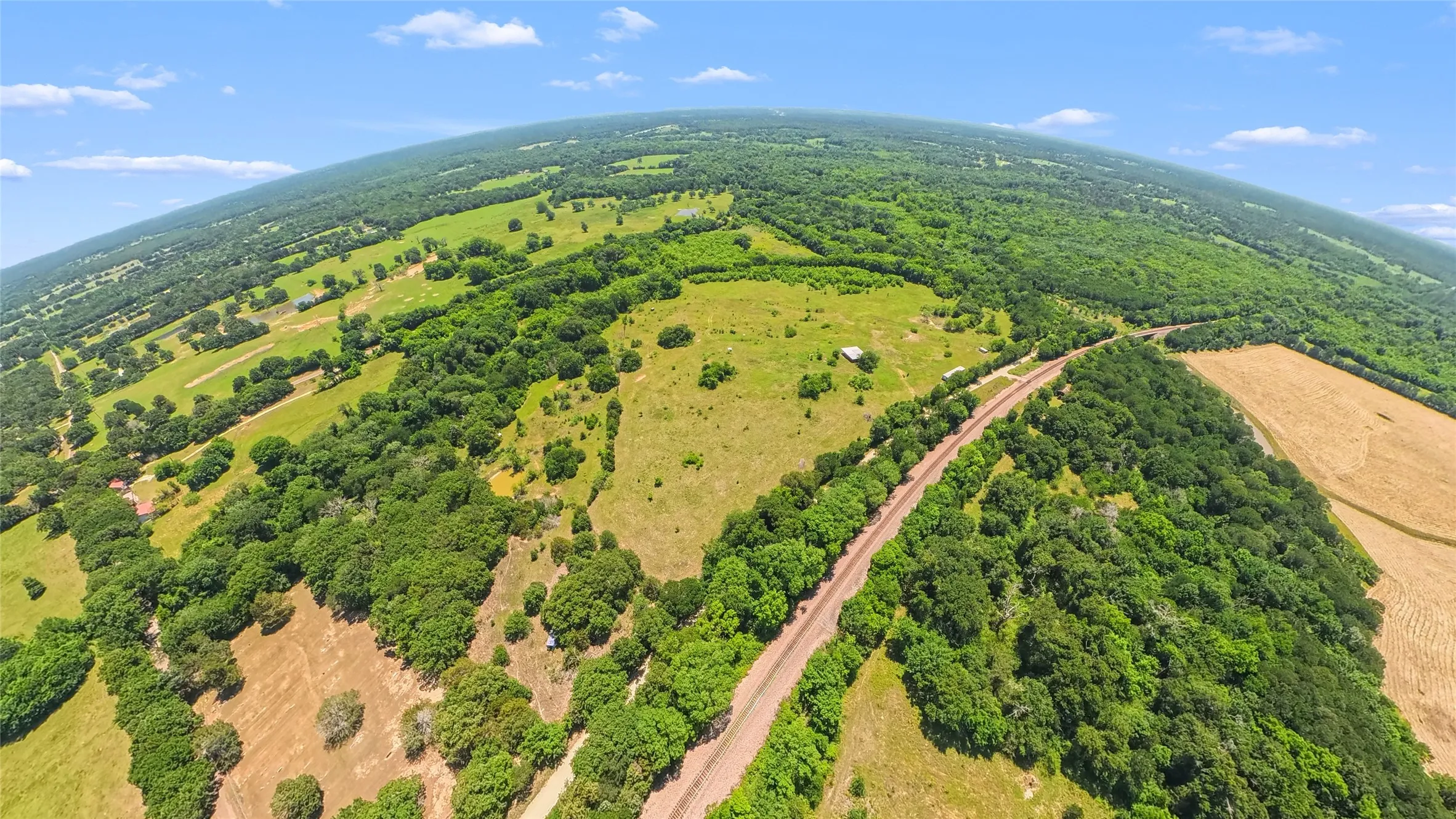Expansive acreage featuring a mix of cleared pasture, wooded areas, and agricultural fields