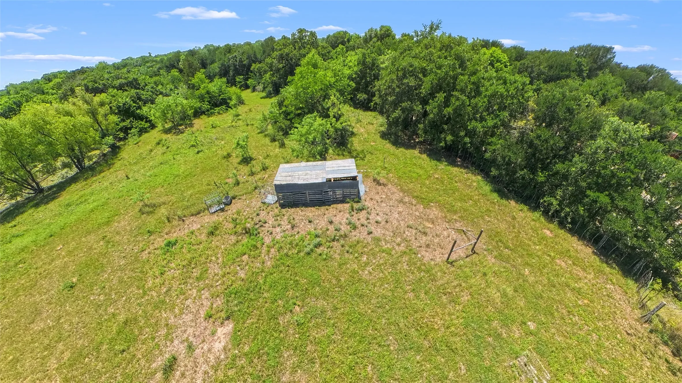 Expansive hillside property featuring diverse tree cover and a structure with an industrial roof