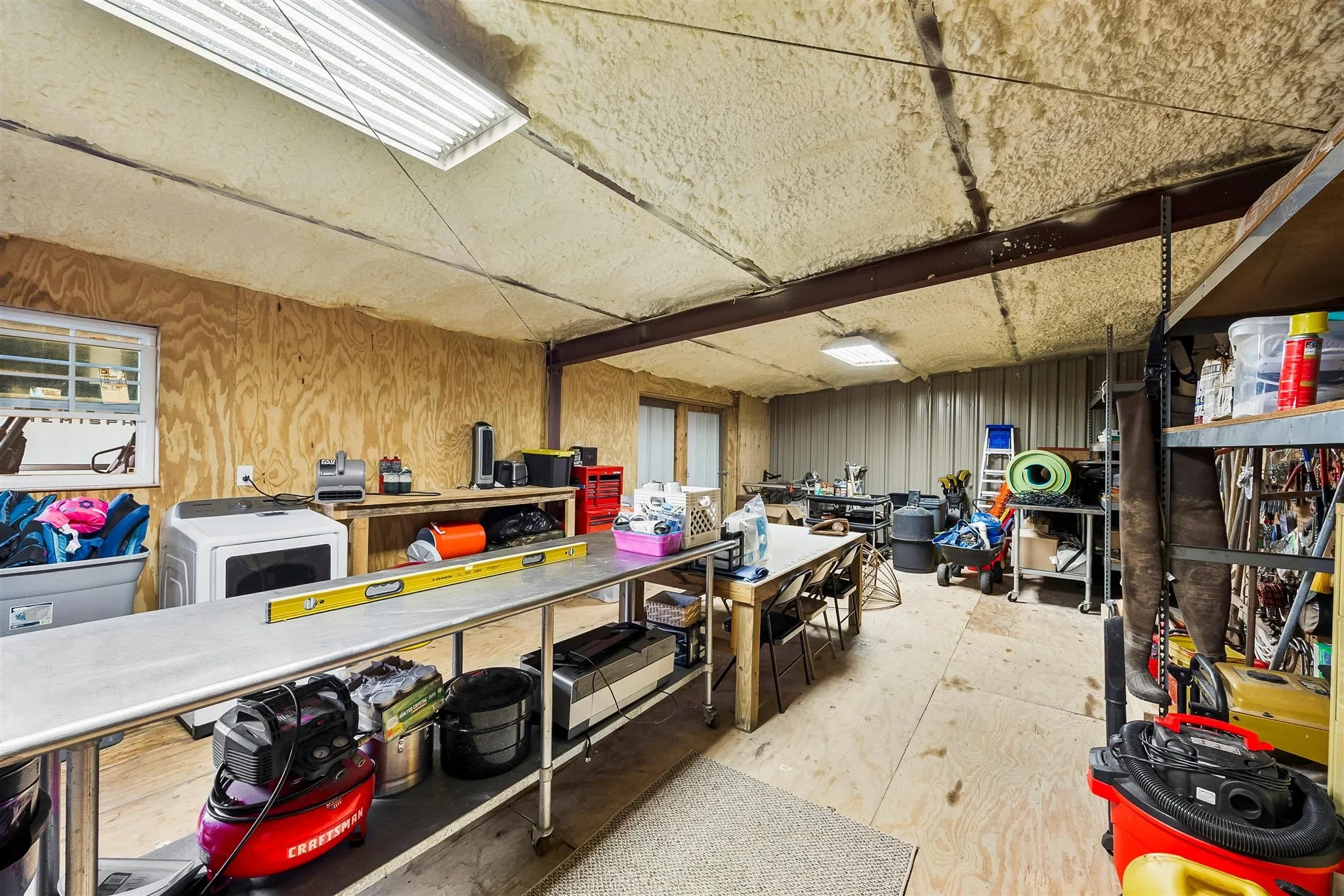 Versatile utility space featuring exposed metal beams, wood paneling, and an insulated ceiling