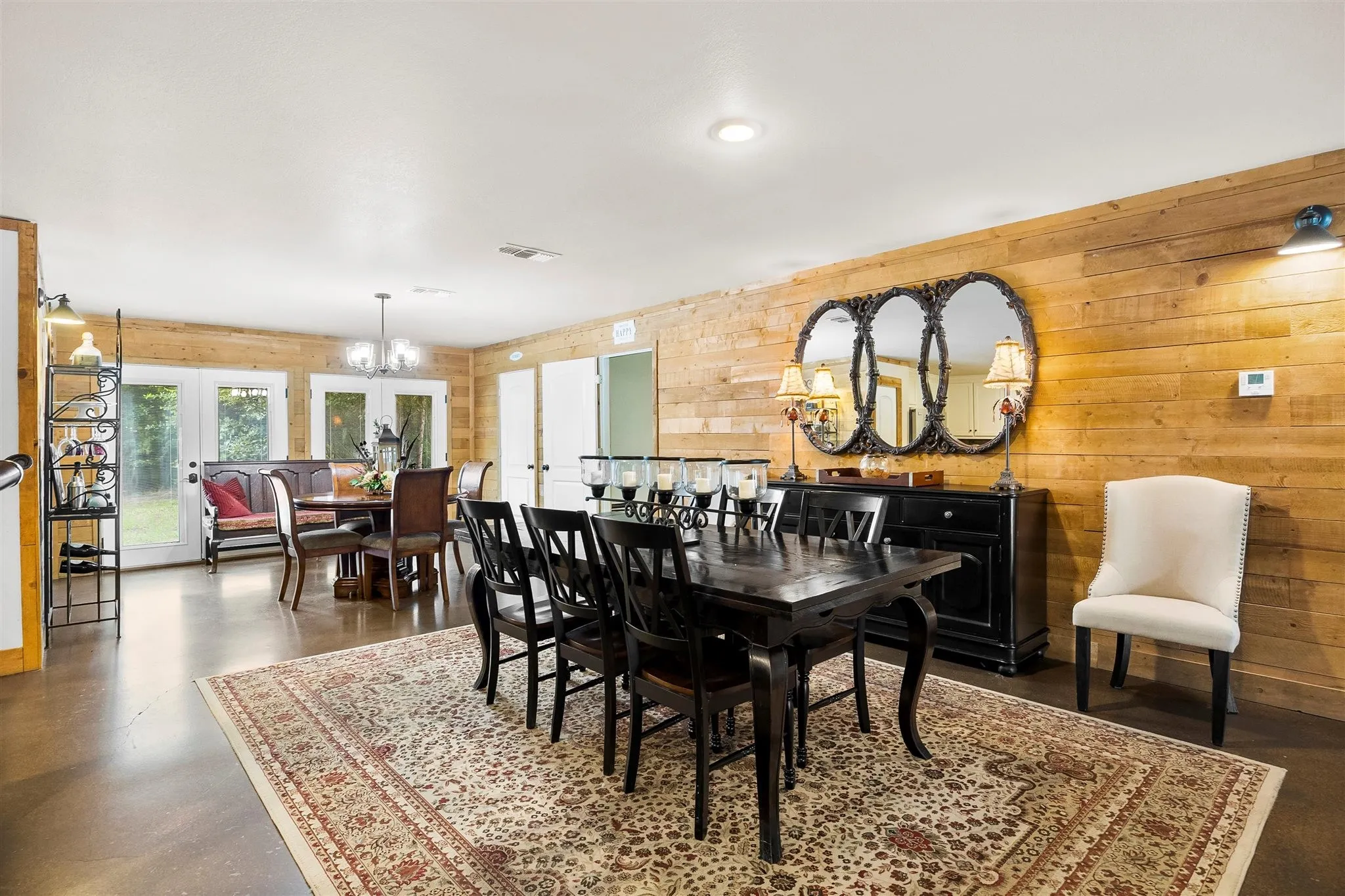 Expansive dining area featuring wood-paneled walls, recessed lighting, and a large area rug