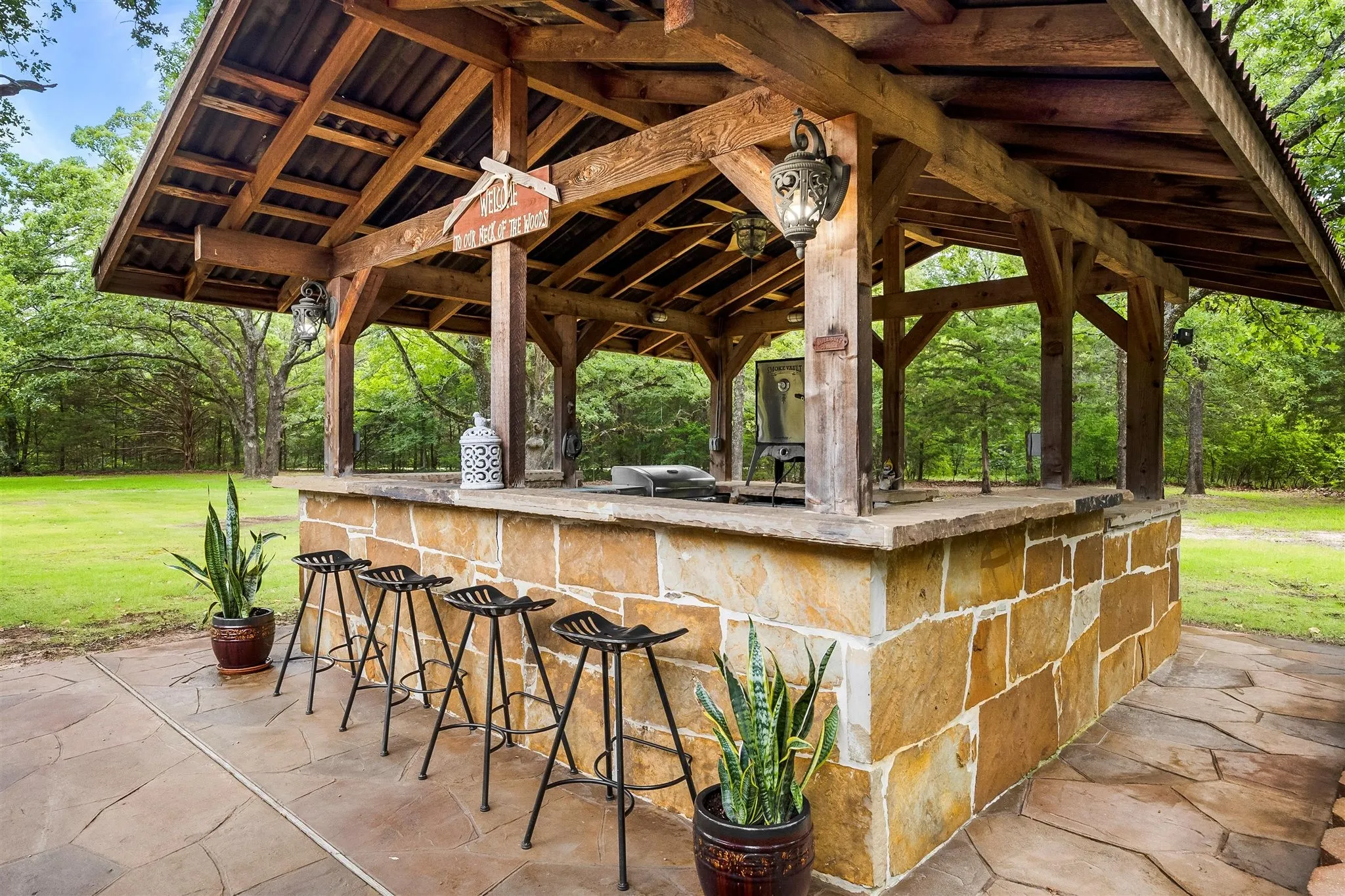 Outdoor stone bar with a wood-beam pavilion and flagstone patio