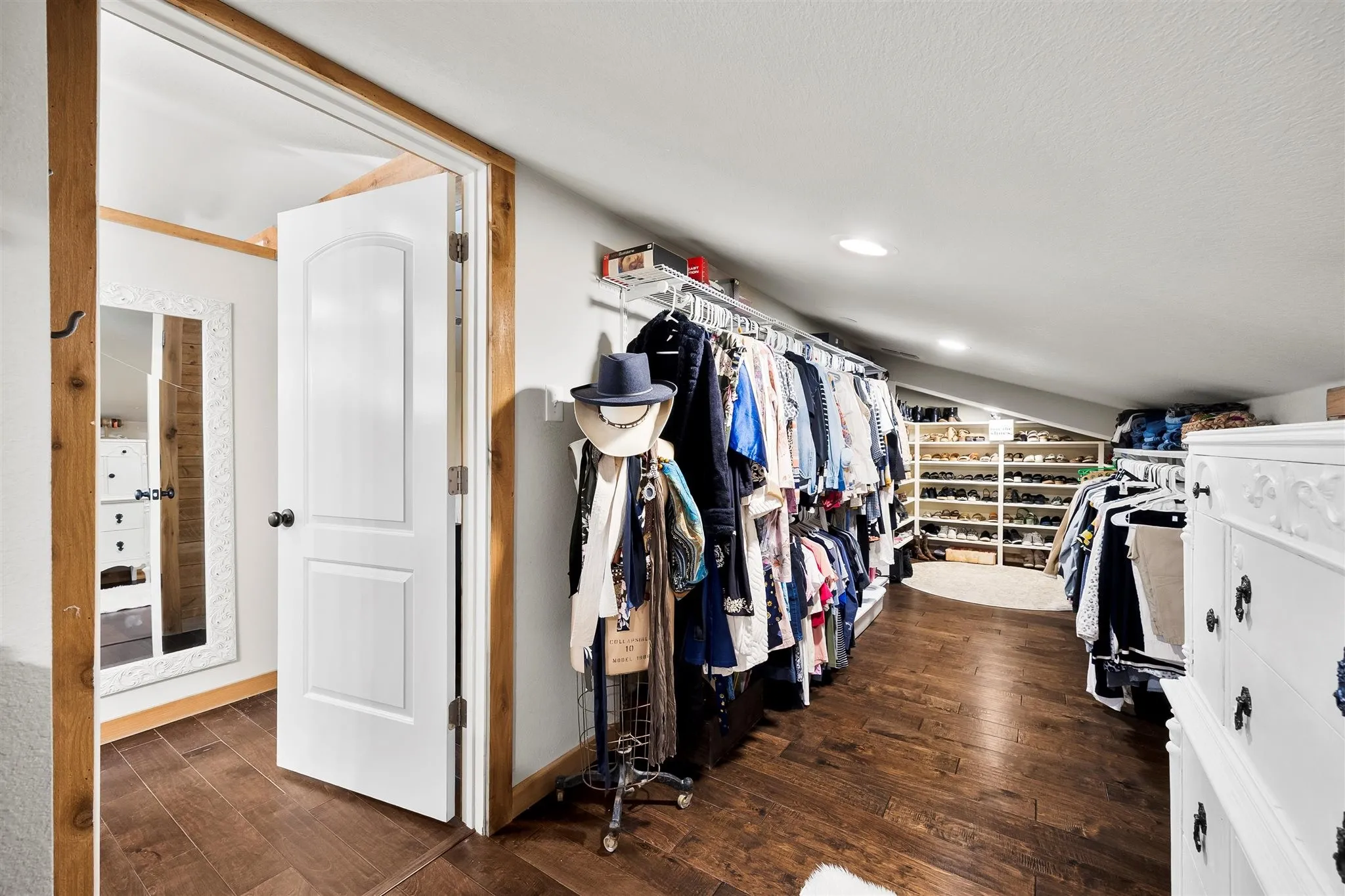 Spacious walk-in closet featuring wood-finish flooring, recessed lighting, and extensive built-in shelving