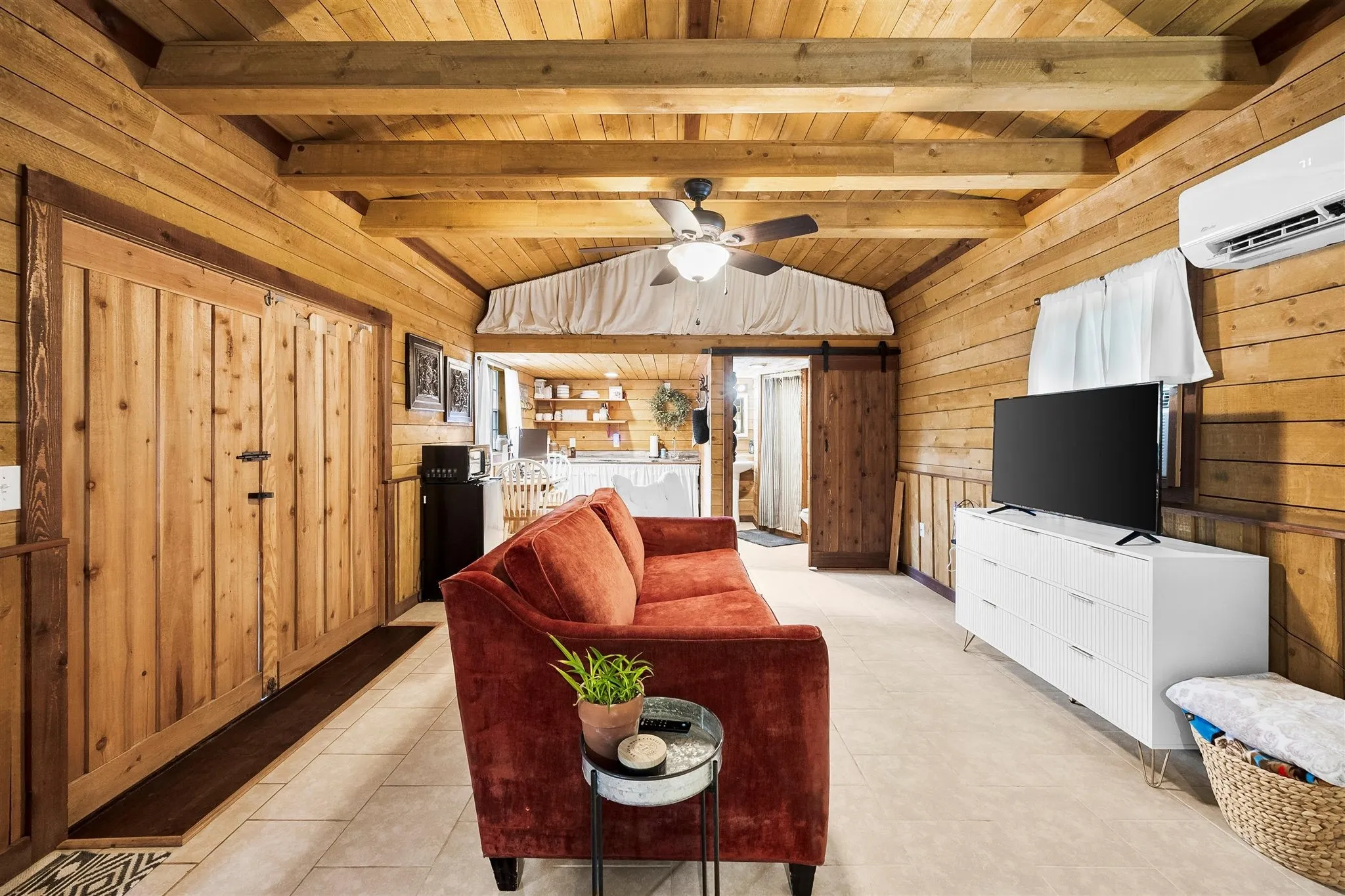 Vaulted wood-paneled ceiling with exposed beams and a ceiling fan
