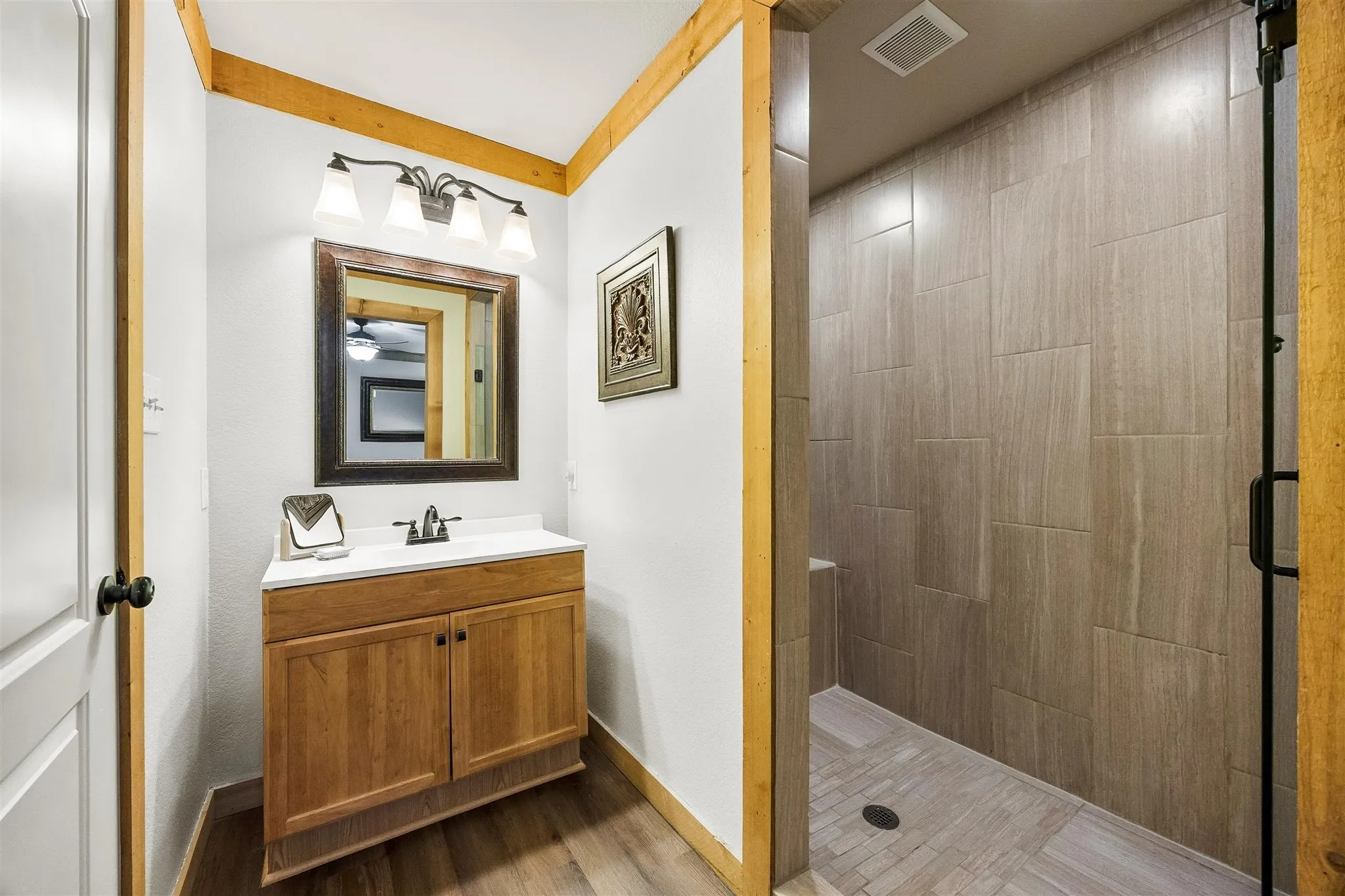 Bathroom featuring a wood-finish vanity with an integrated sink and a framed mirror