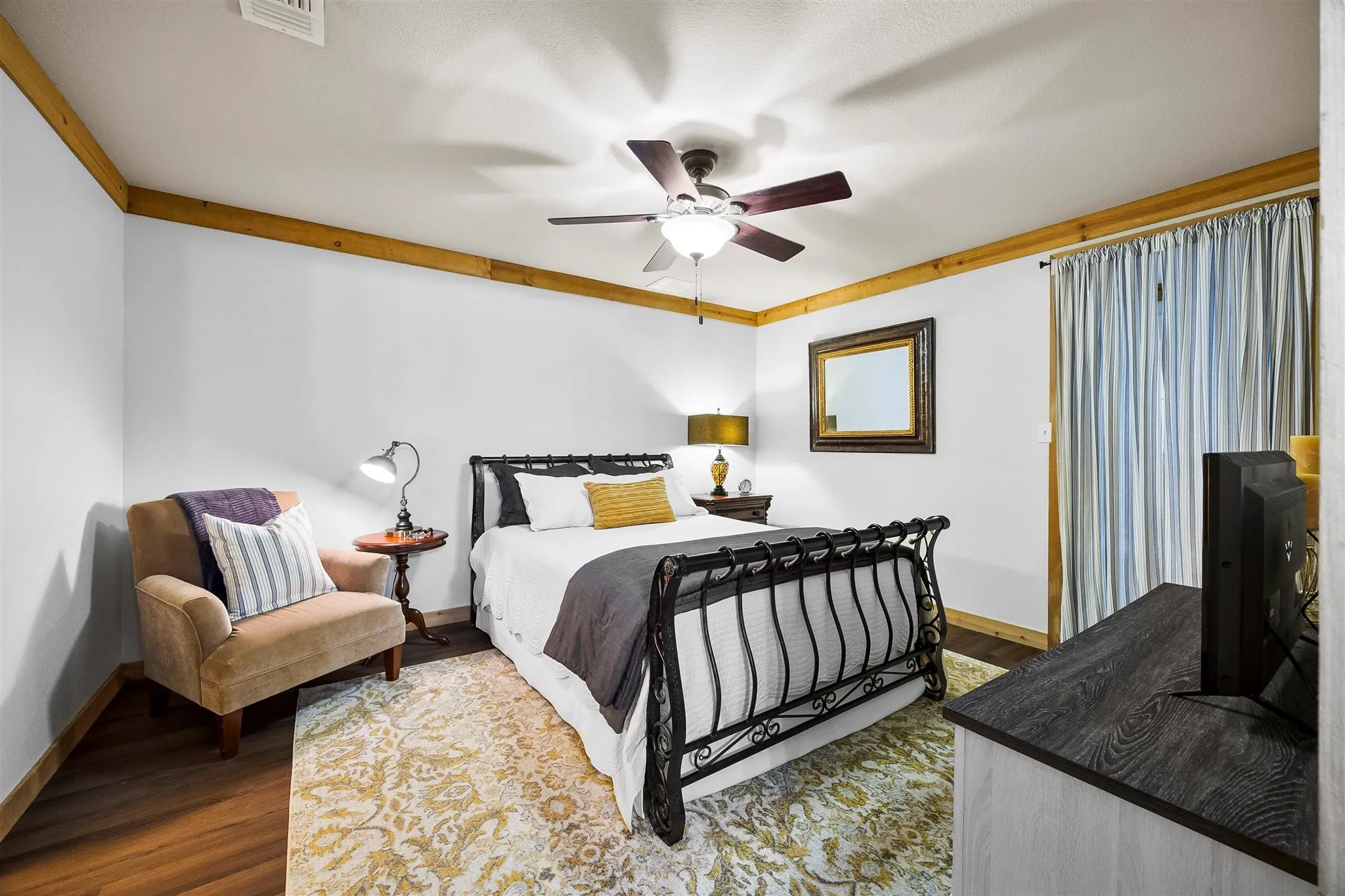 Bedroom featuring wood-finish flooring, white walls, and wood trim detailing