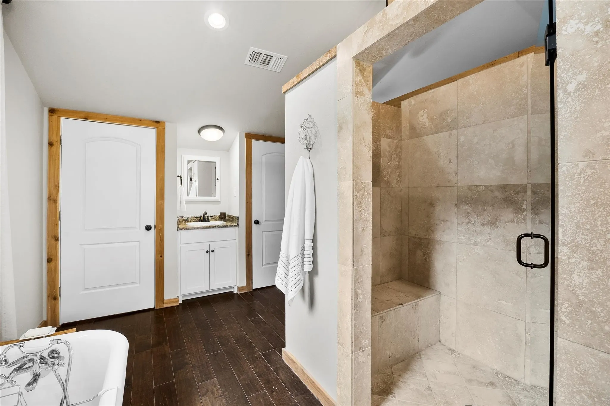 Walk-in shower with natural stone-look tile, integrated bench, and clear glass enclosure