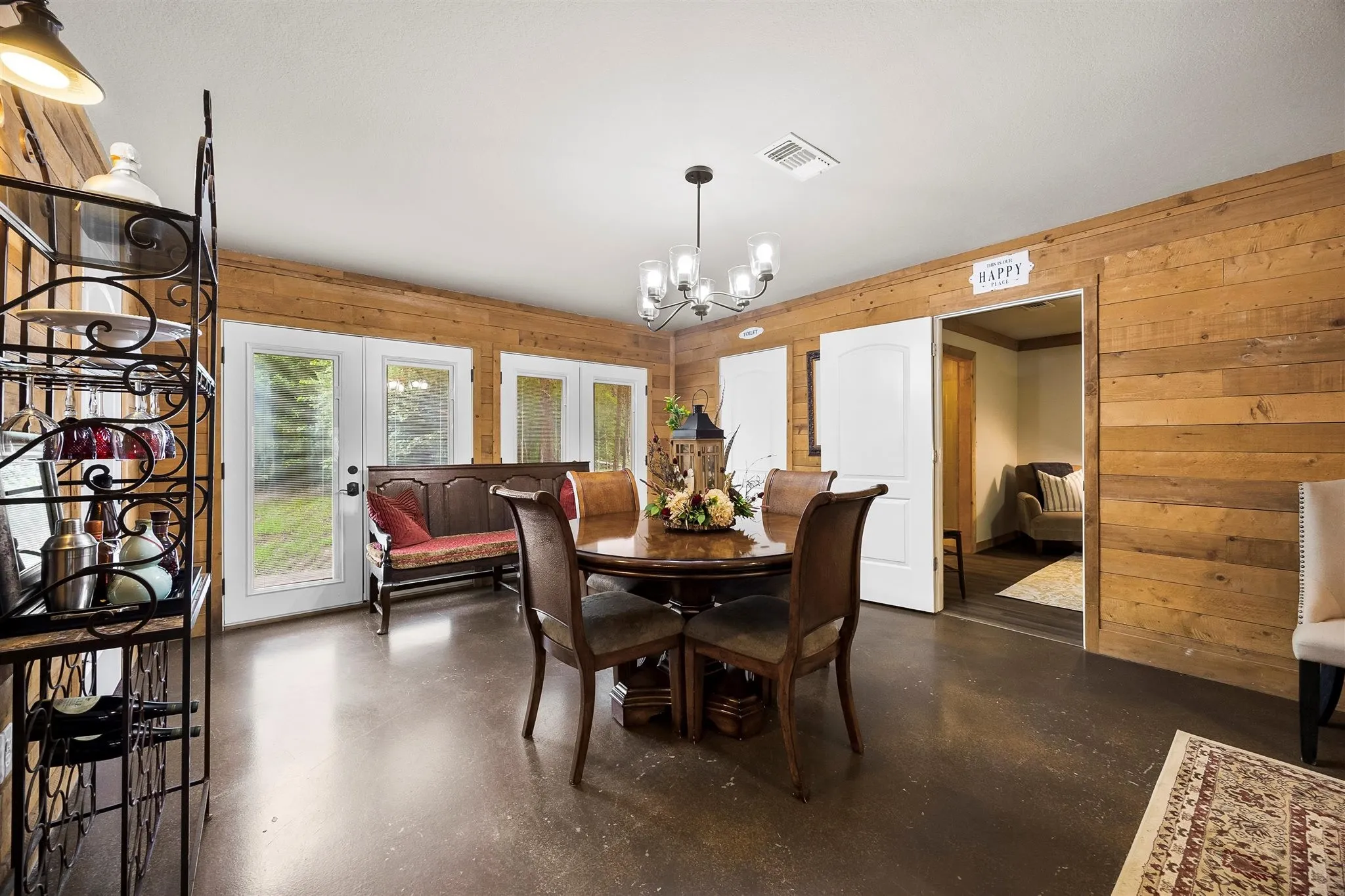 Spacious room featuring wood-paneled walls, dark concrete flooring, and multiple glass-paned doors
