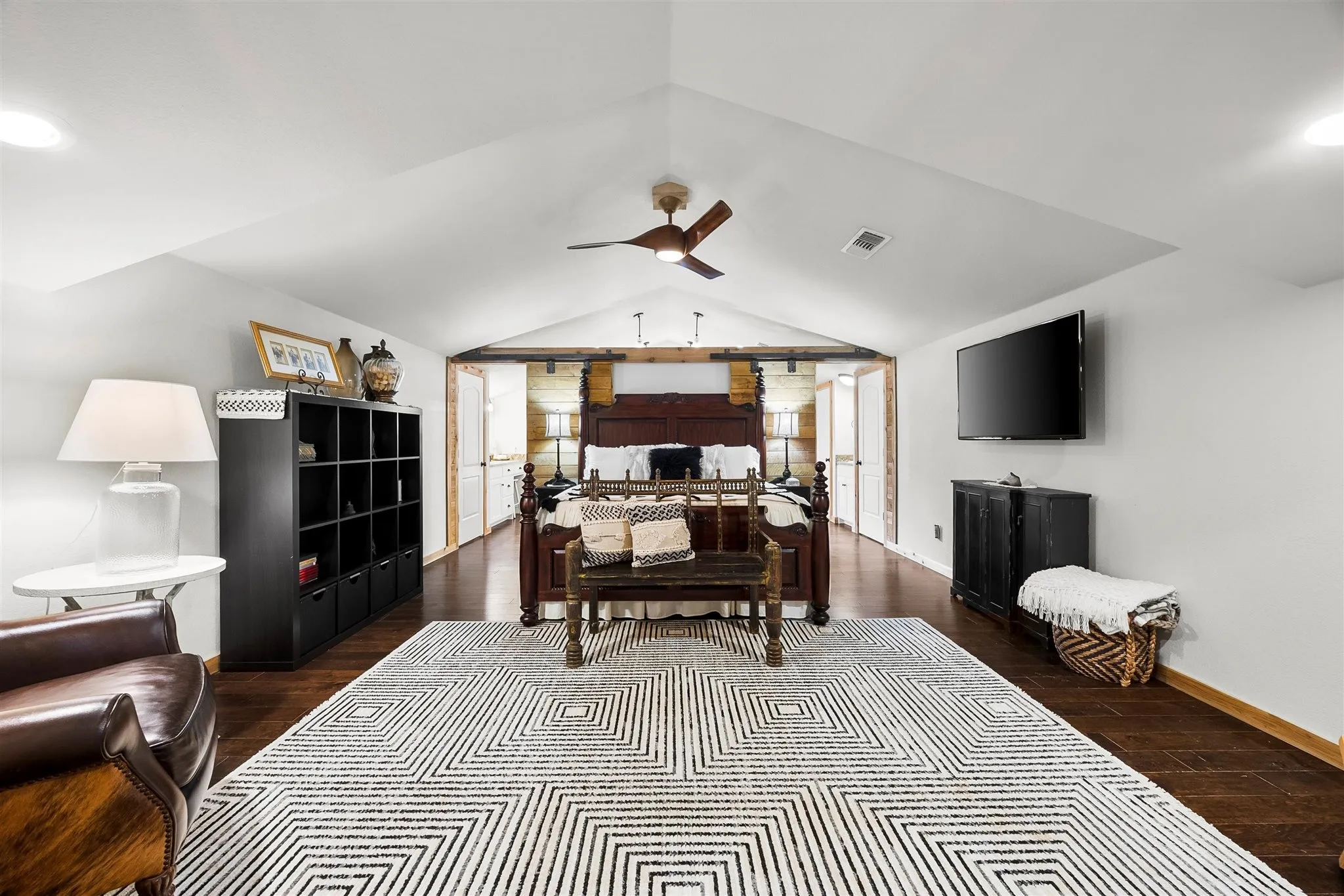 Spacious room featuring rich wood-finish flooring, a vaulted ceiling, and recessed lighting