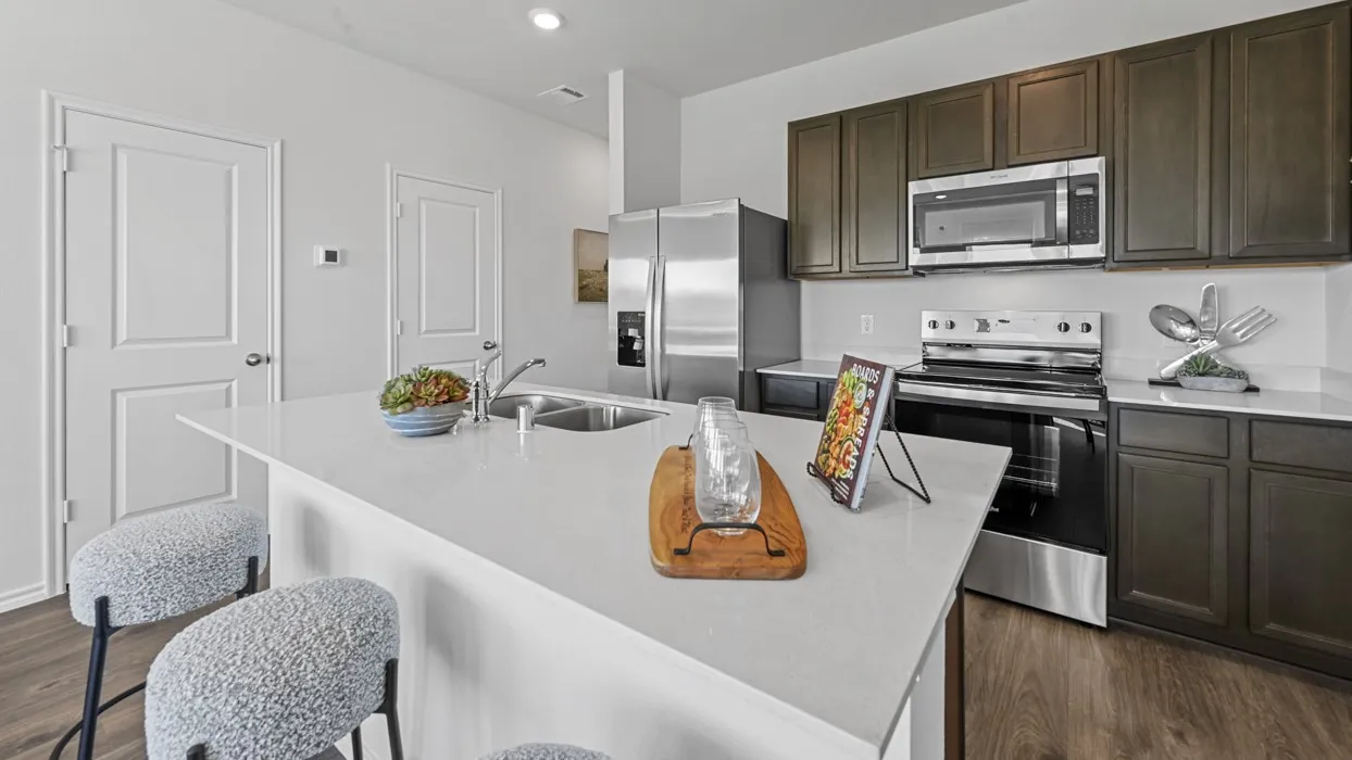 Modern kitchen featuring dark wood-finish cabinetry, stainless steel appliances, white countertops, and wood-finish flooring