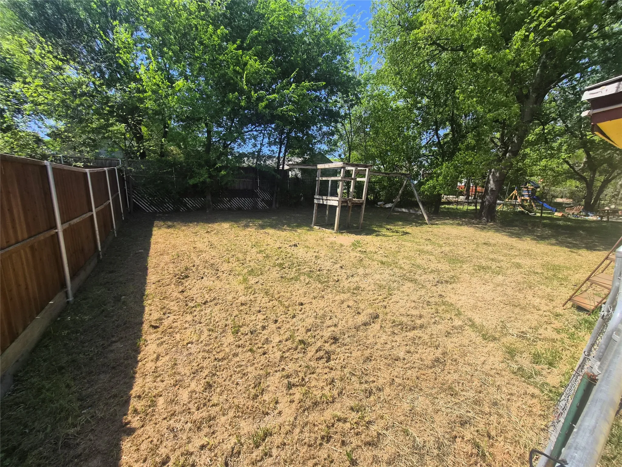 Spacious backyard featuring wood fencing and mature trees
