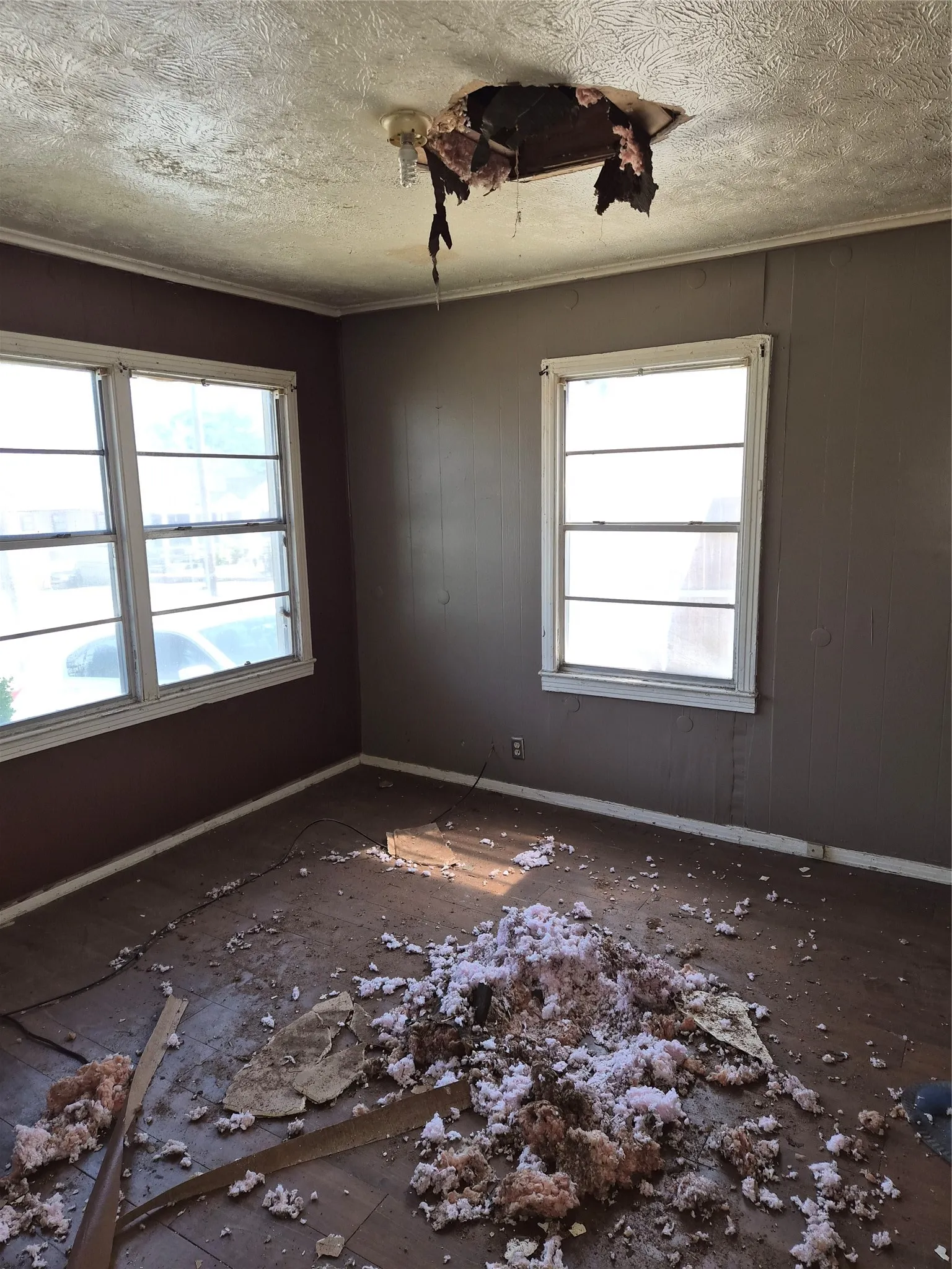 Room featuring two windows, textured ceiling, baseboard trim, and a ceiling light fixture