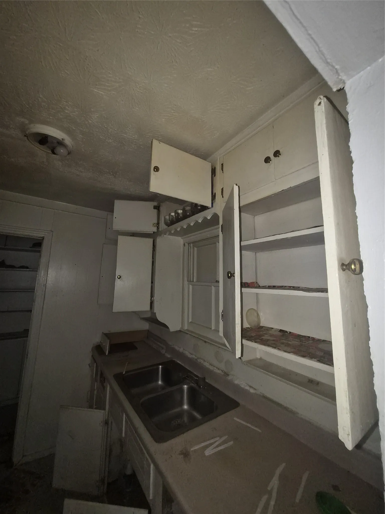 Kitchen featuring a double basin stainless steel sink, built-in upper cabinetry, and a textured ceiling