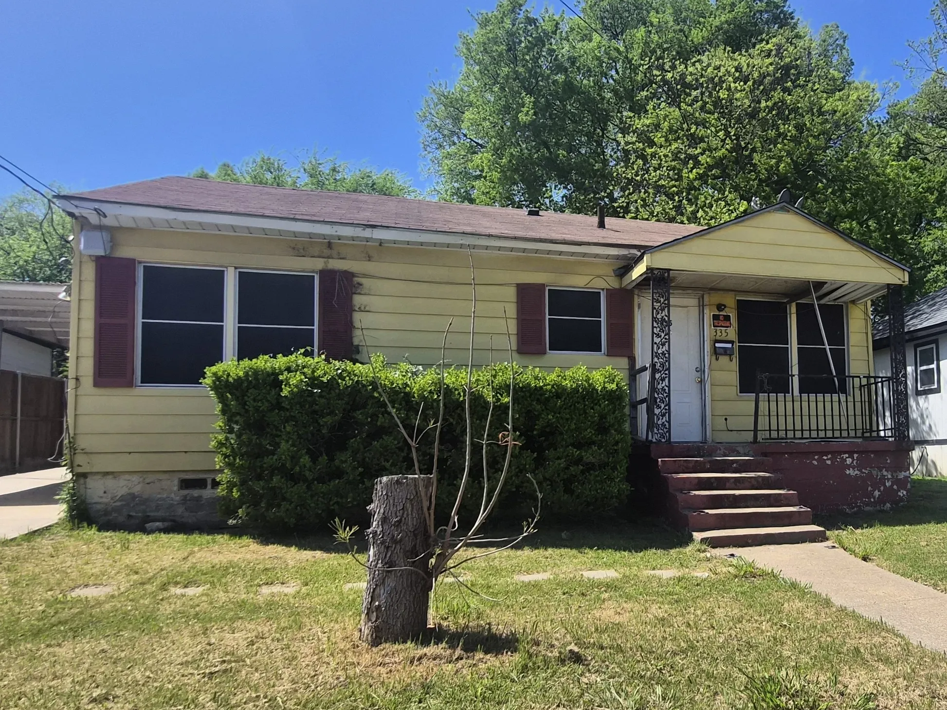 Yellow exterior with red shutters, a covered front porch, and black iron railings