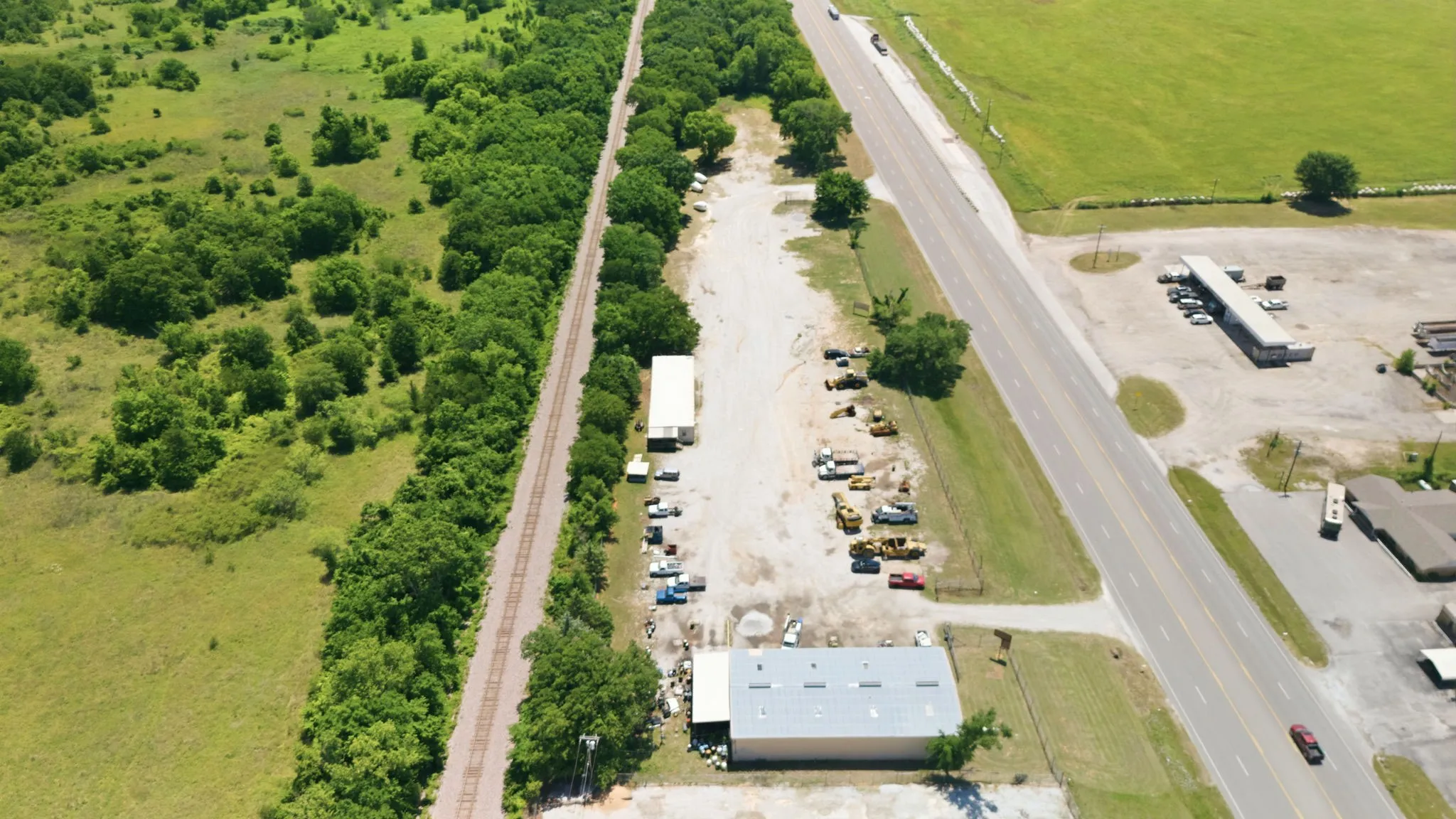 Aerial perspective showcasing a commercial property with a light-colored metal roof building and a smaller adjacent structure