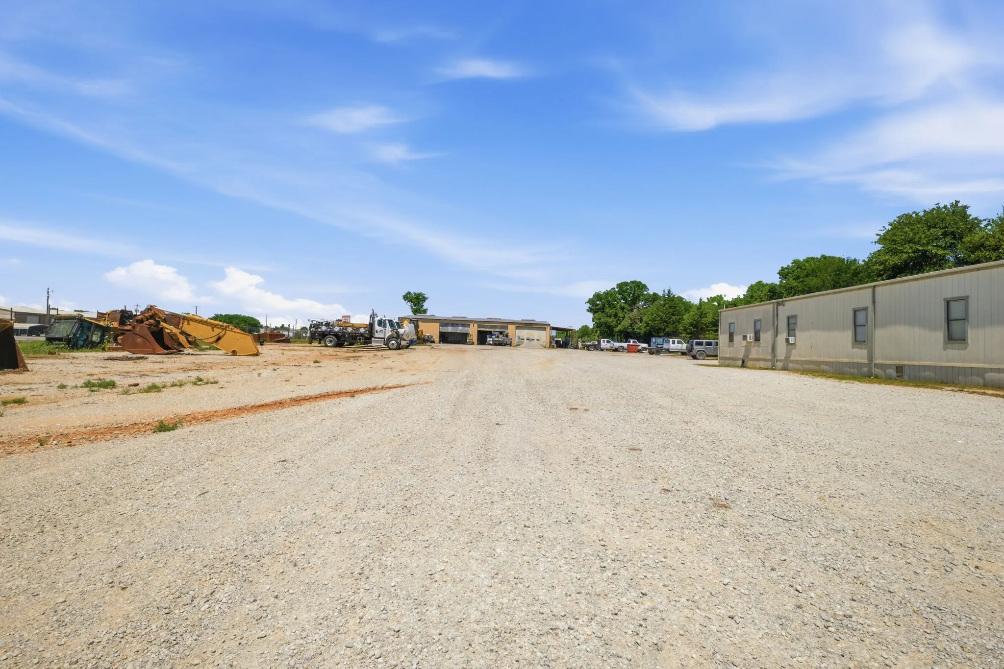 Expansive gravel lot with multiple buildings present