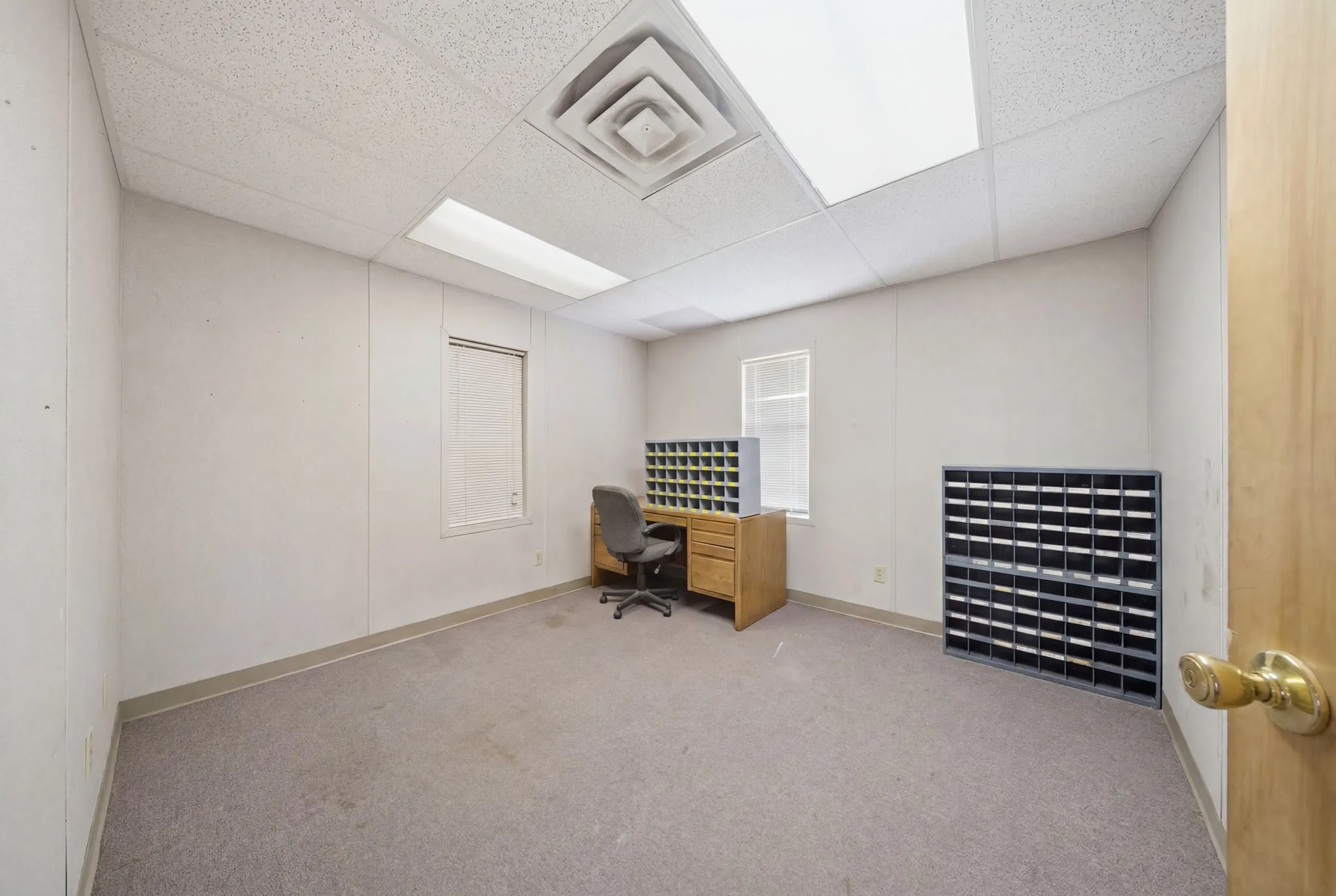 Office space featuring light-colored panel walls, neutral carpeting, and a drop ceiling with recessed lighting
