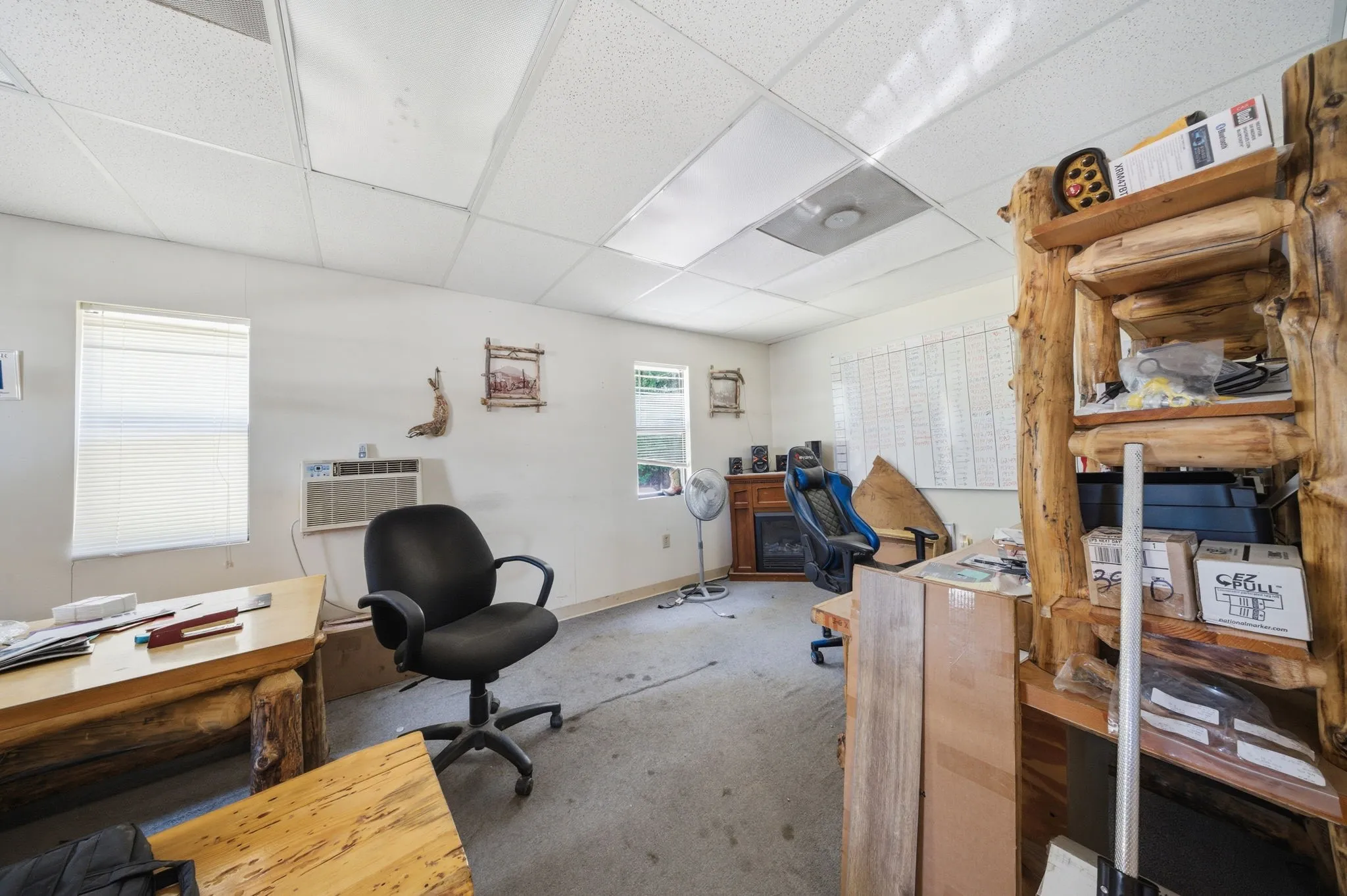Spacious room featuring multiple windows, a drop ceiling with integrated lighting, and a wall-mounted air conditioning unit
