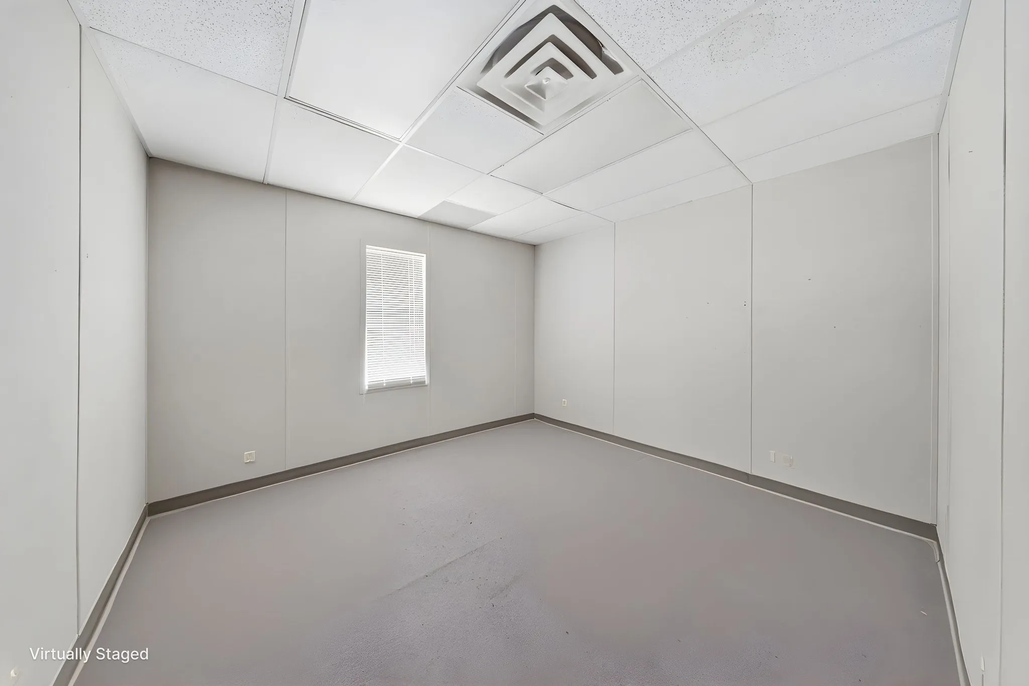 Spacious room with light gray walls, gray flooring, and a white acoustical tile ceiling