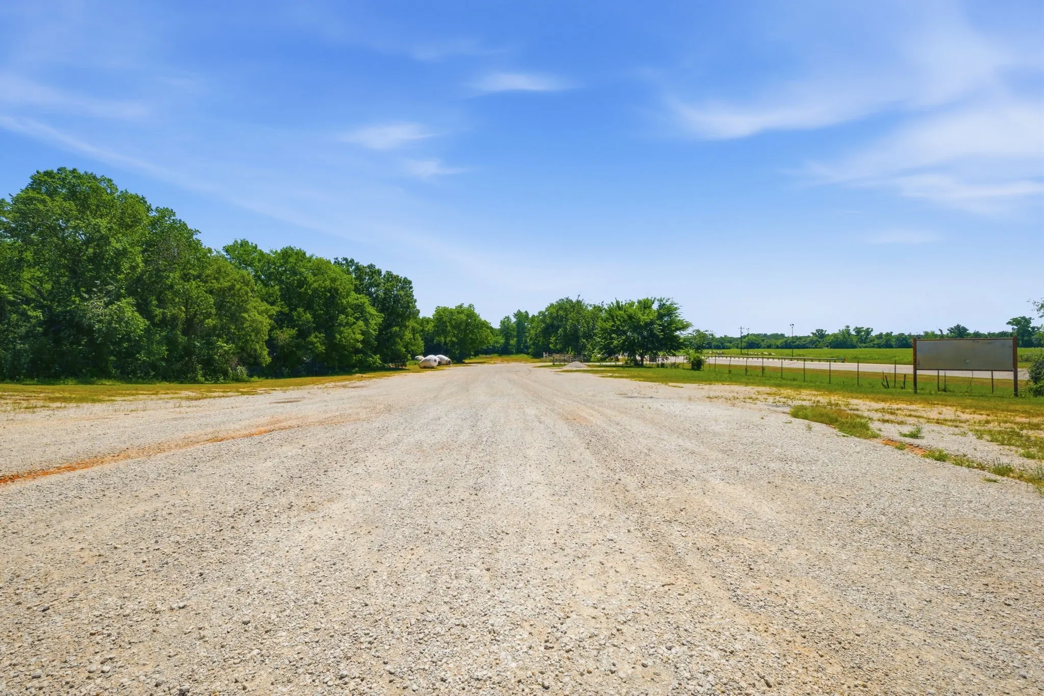 Expansive gravel lot with a tree line border