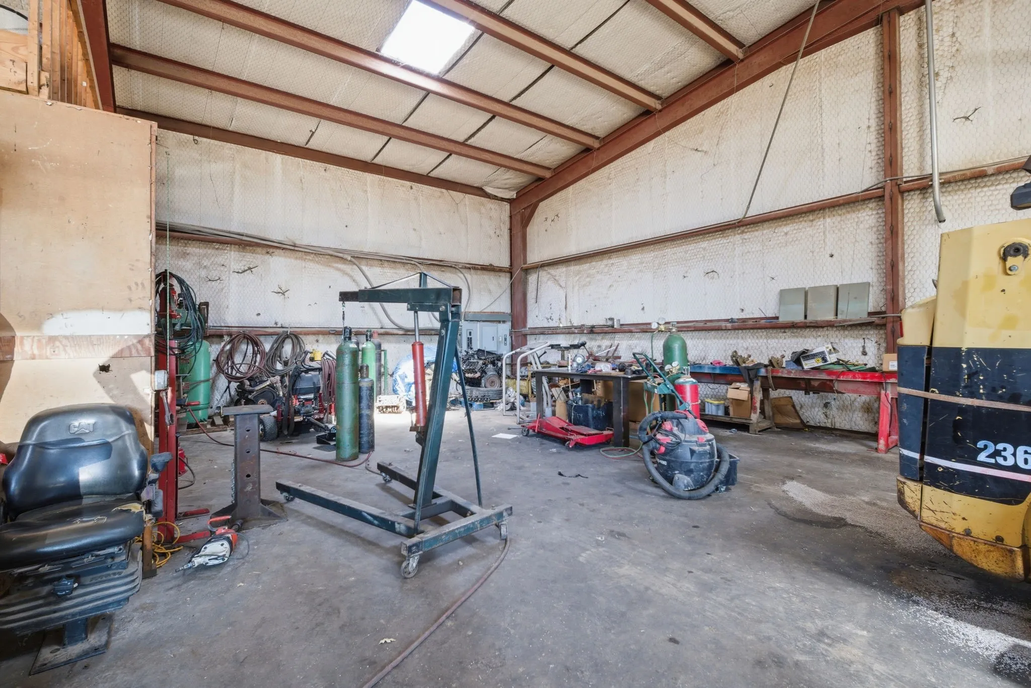 Spacious industrial warehouse interior featuring an open layout, high ceilings with exposed metal trusses, and skylight illumination