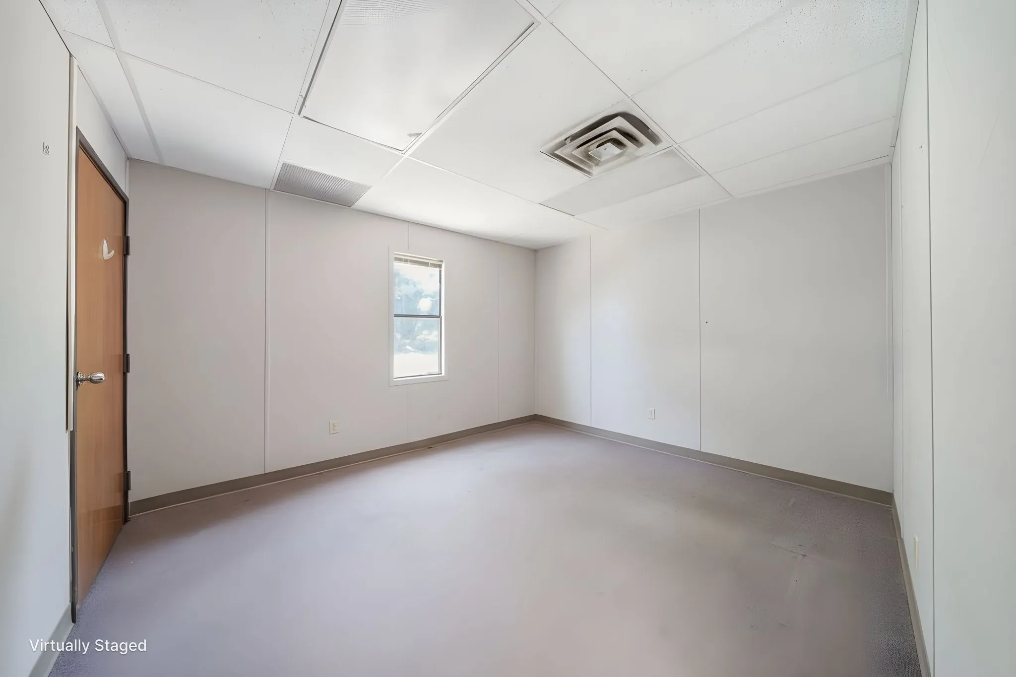 Spacious room featuring light-toned walls, a drop ceiling, and an air vent