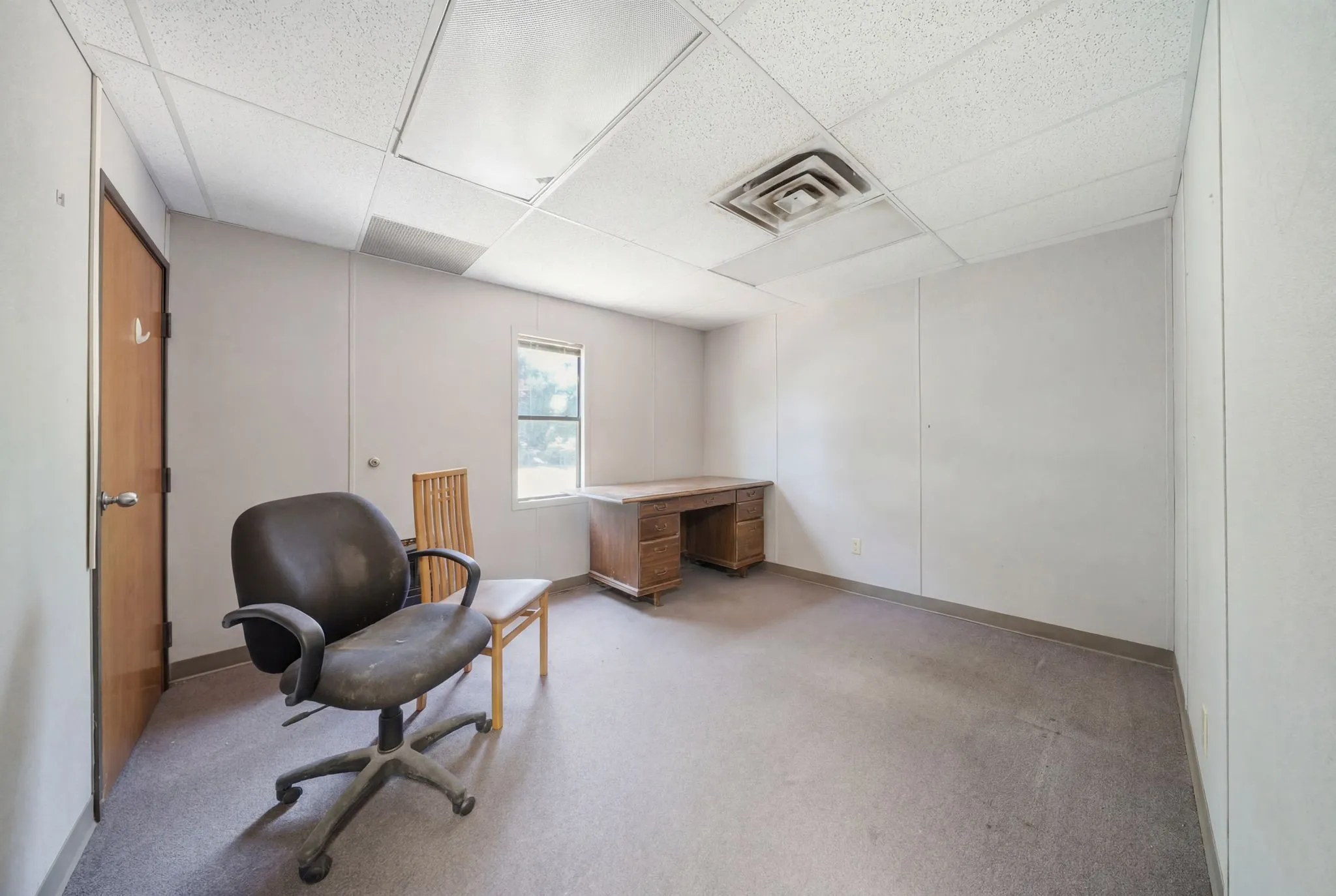 Room featuring a drop ceiling, wall-to-wall carpeting, and a window providing natural light