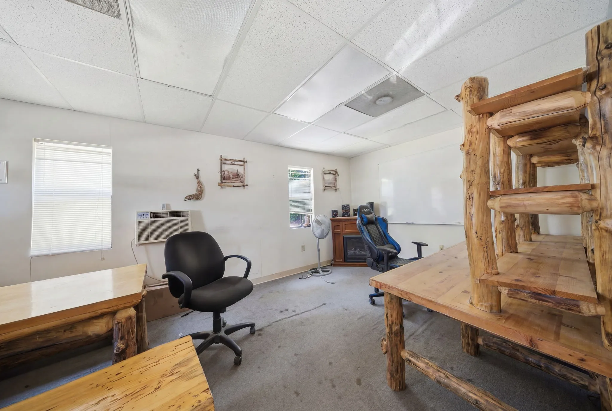 Spacious interior room with wood-finish office furniture, white walls, and a drop ceiling