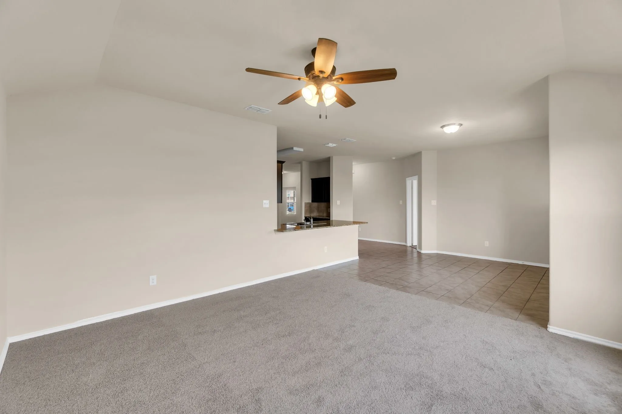 Carpeted empty room featuring lofted ceiling and ceiling fan