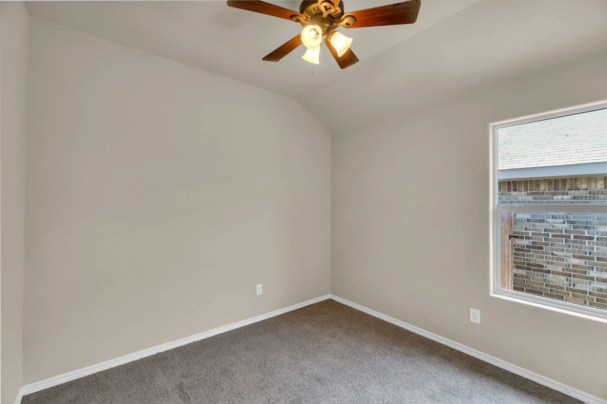 Carpeted empty room featuring ceiling fan and lofted ceiling