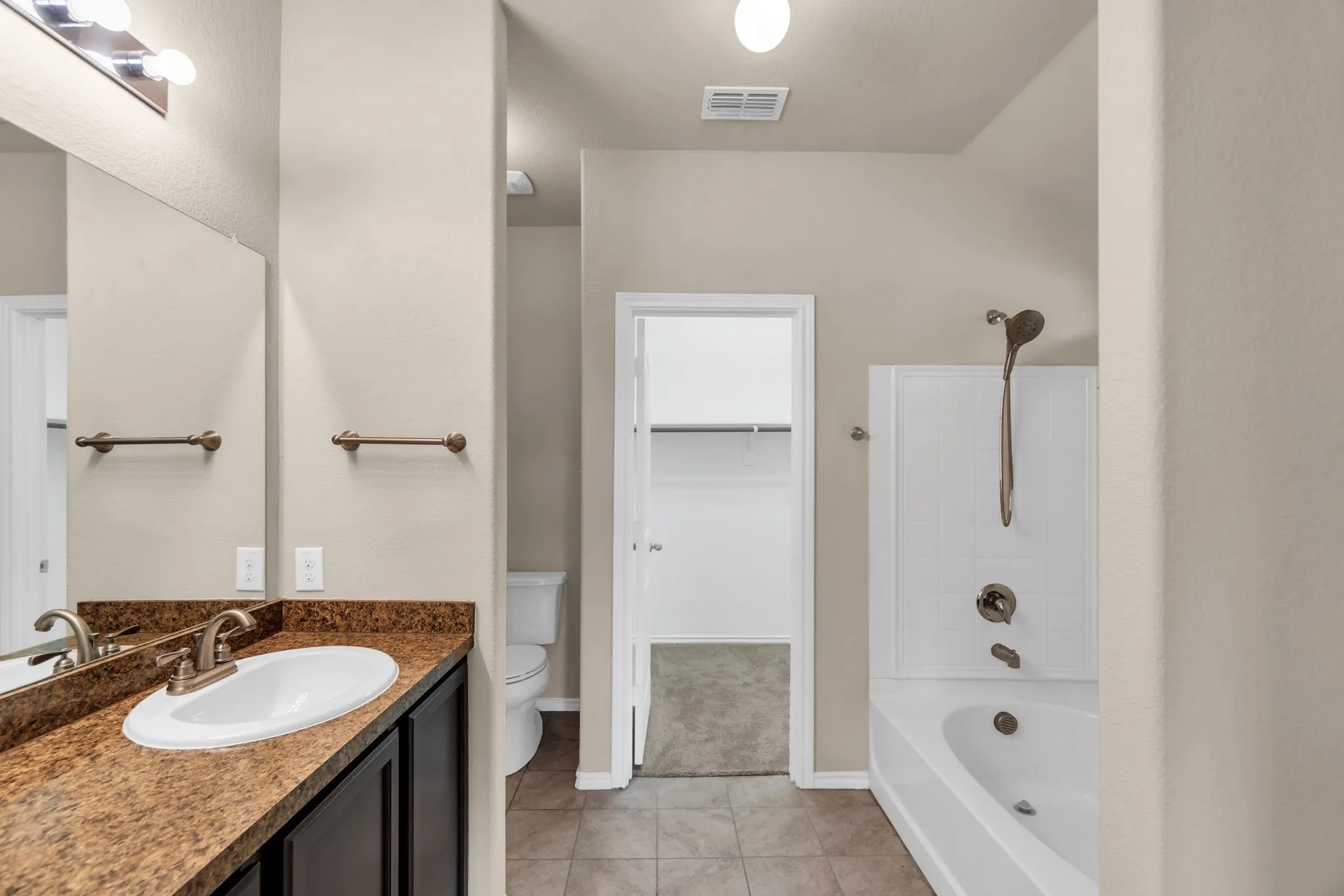 Full bathroom with tile floors,  shower combination, toilet, and large vanity