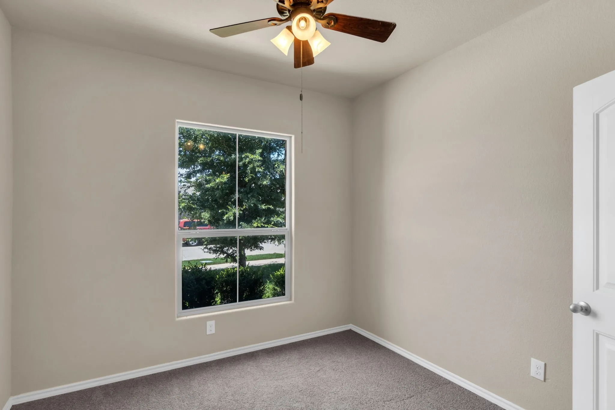 Carpeted empty room featuring ceiling fan