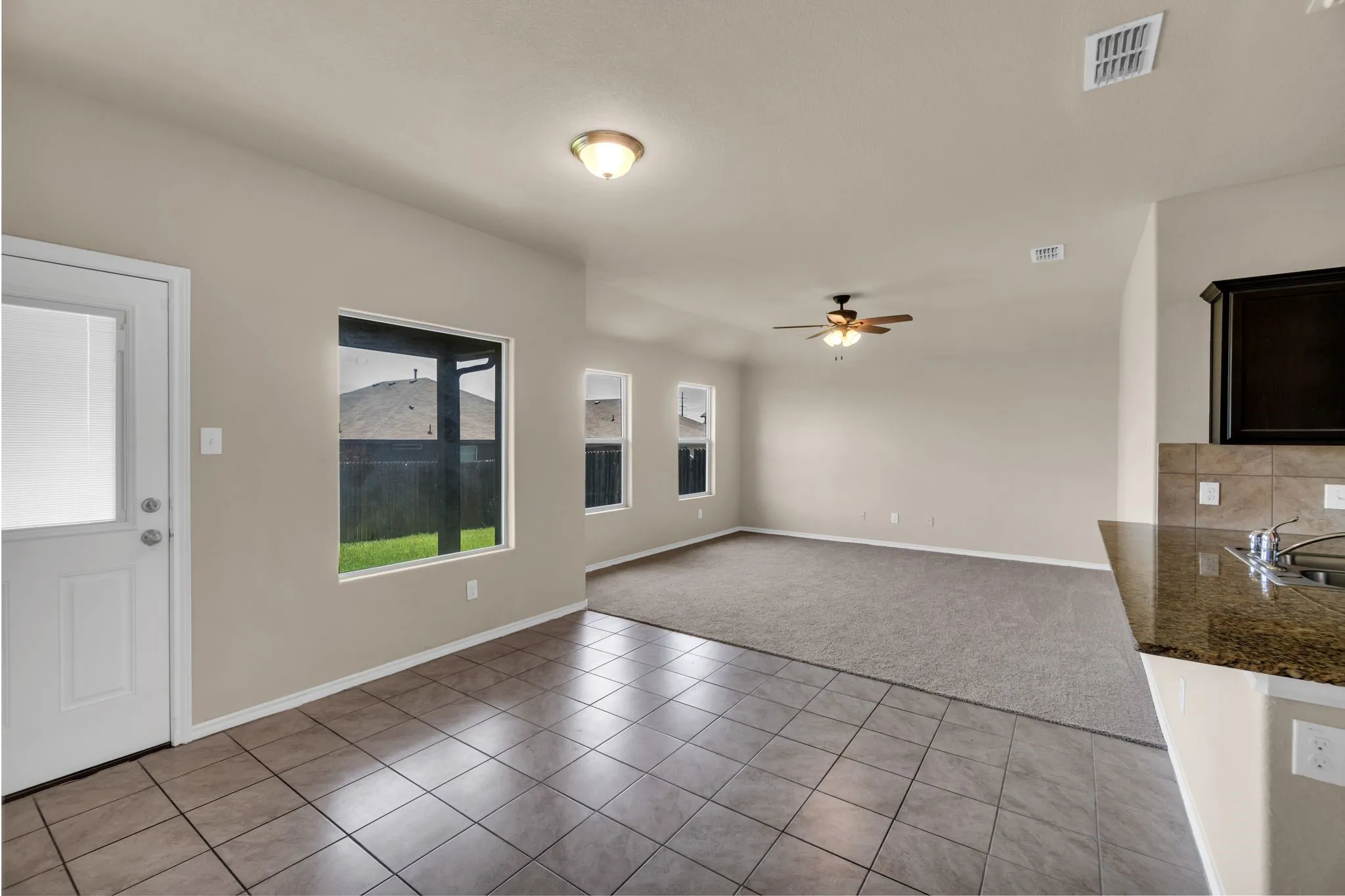 Unfurnished living room featuring ceiling fan, light colored carpet, and sink